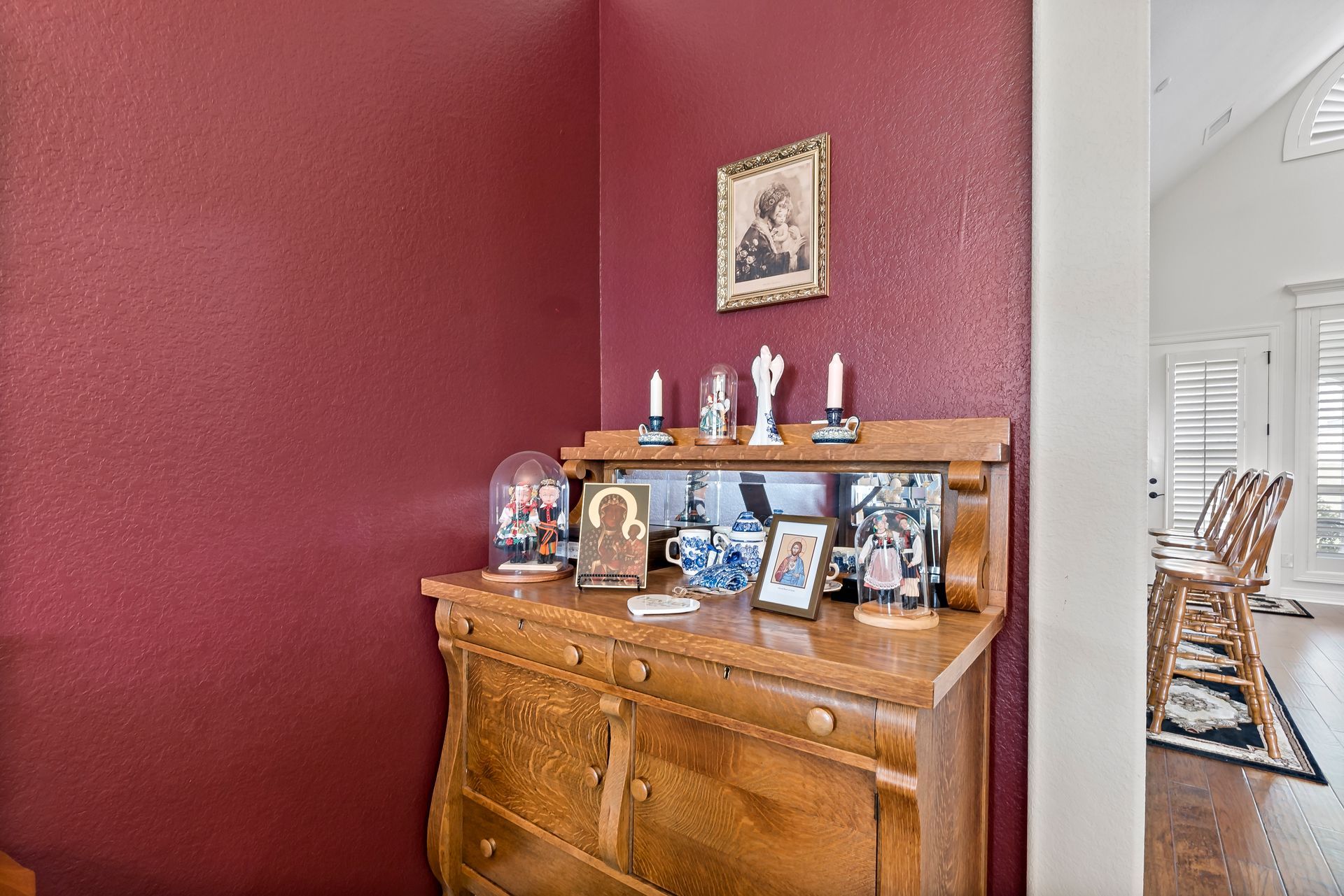 A wooden dresser with a picture on top of it in a room with red walls.