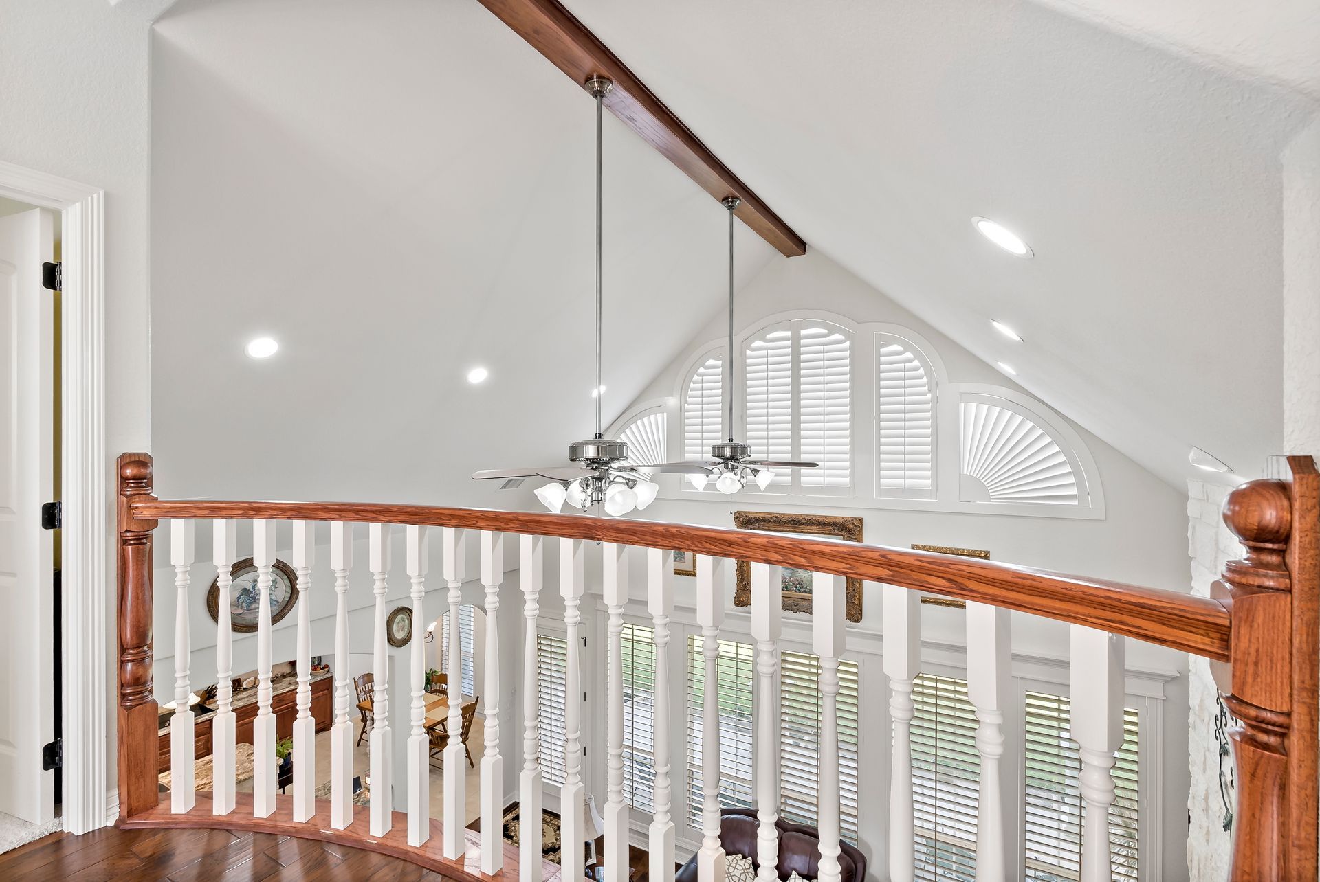 A staircase with a wooden railing and a ceiling fan in a house.