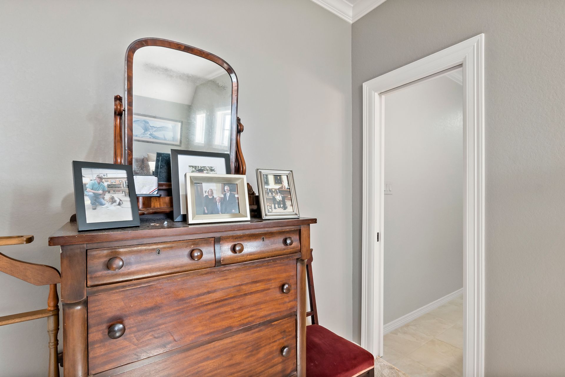 A wooden dresser with a mirror and pictures on it in a bedroom.