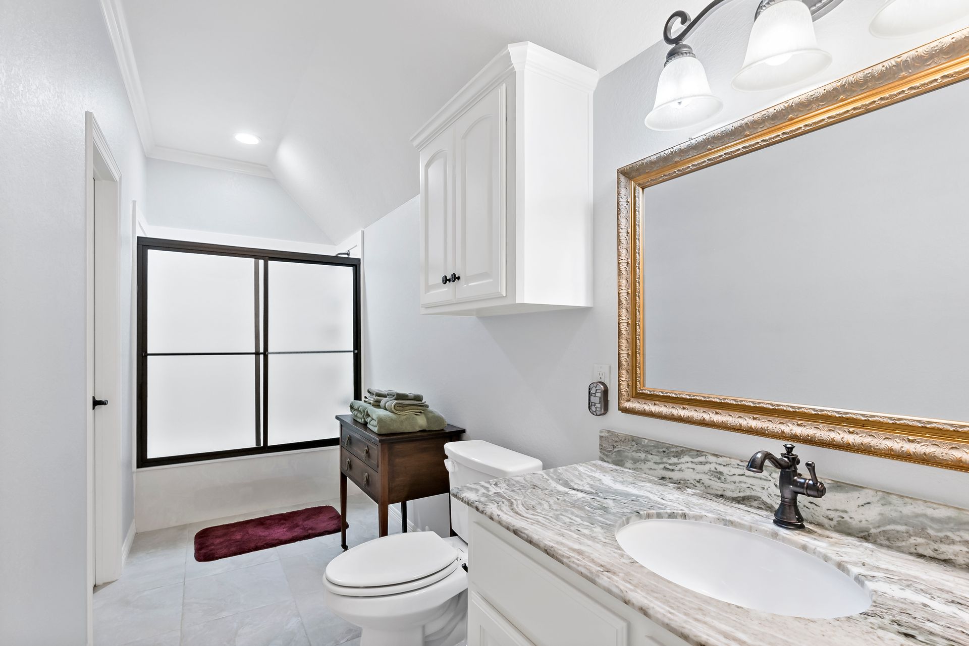 A bathroom with a toilet , sink and mirror.