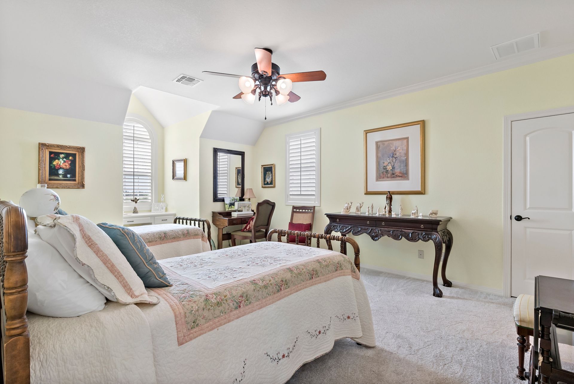 A bedroom with two beds , a desk and a ceiling fan.