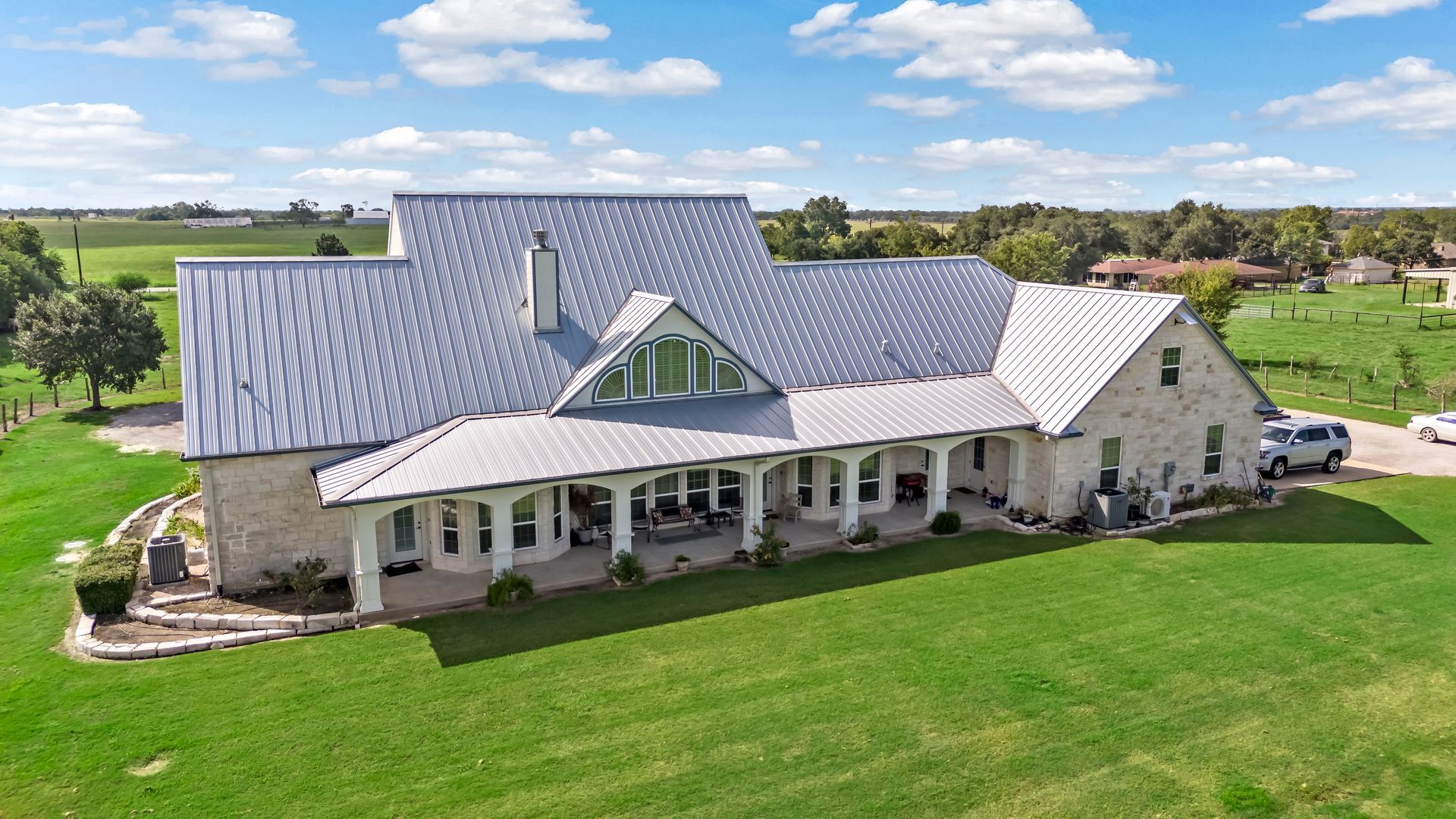 An aerial view of a large house in the middle of a grassy field.