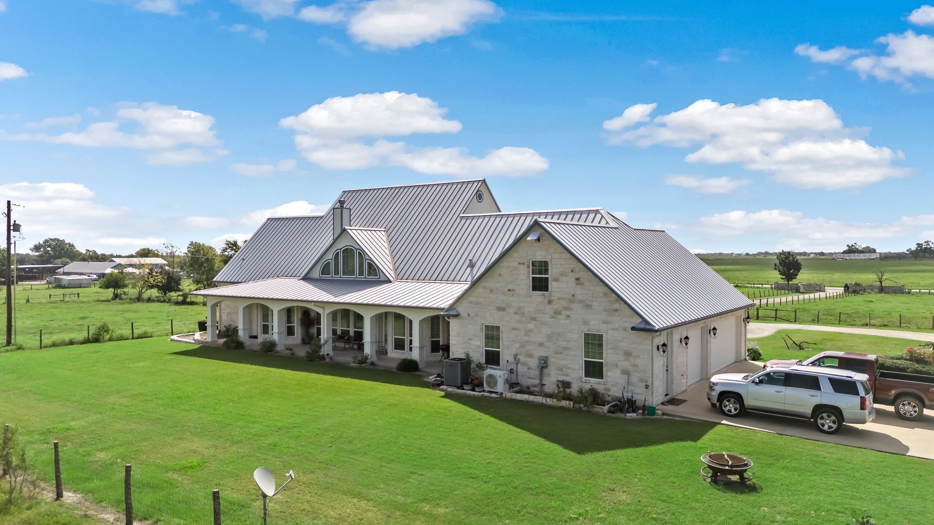 A large white house is sitting on top of a lush green field.