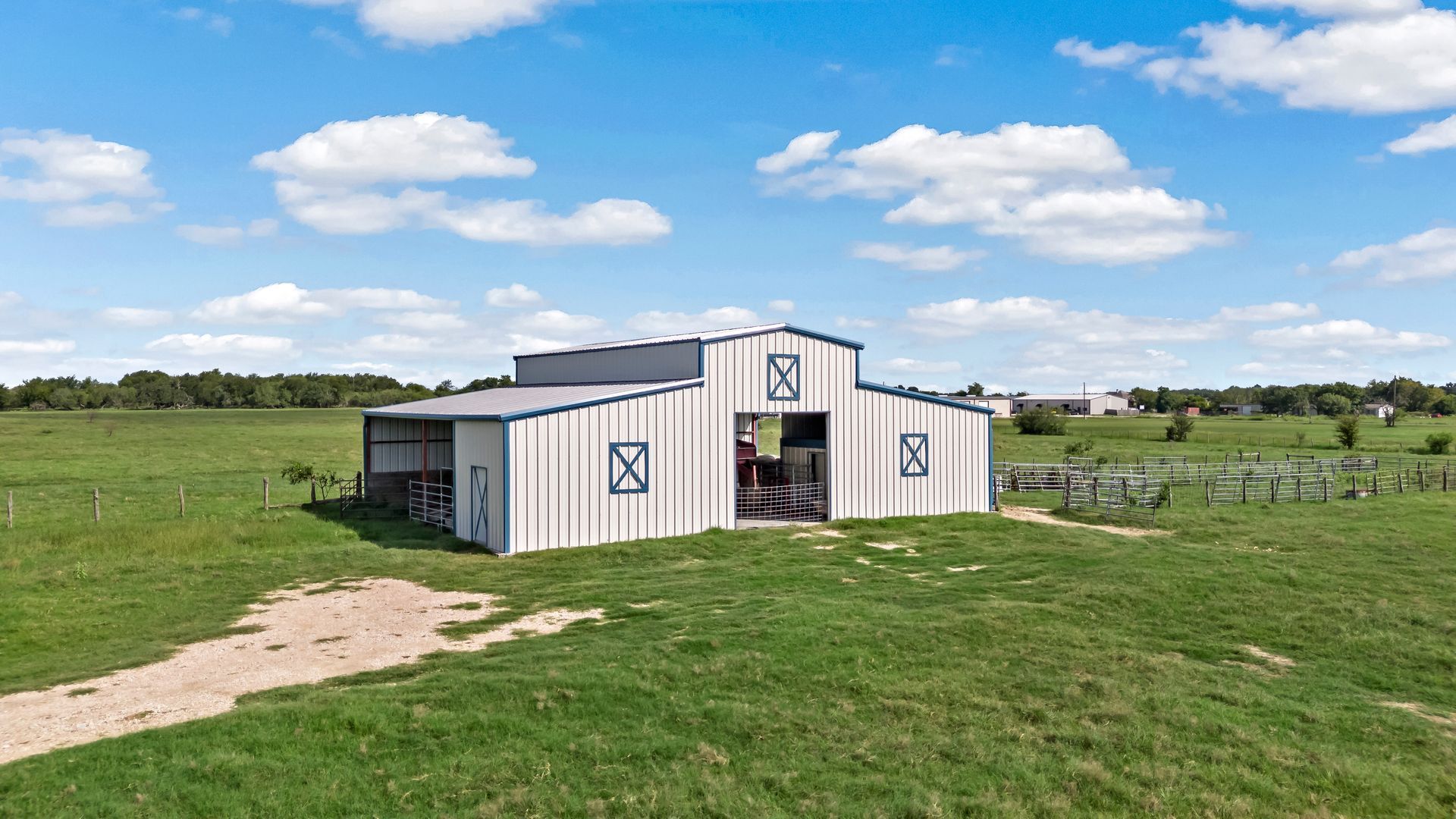 A white barn is sitting in the middle of a grassy field.