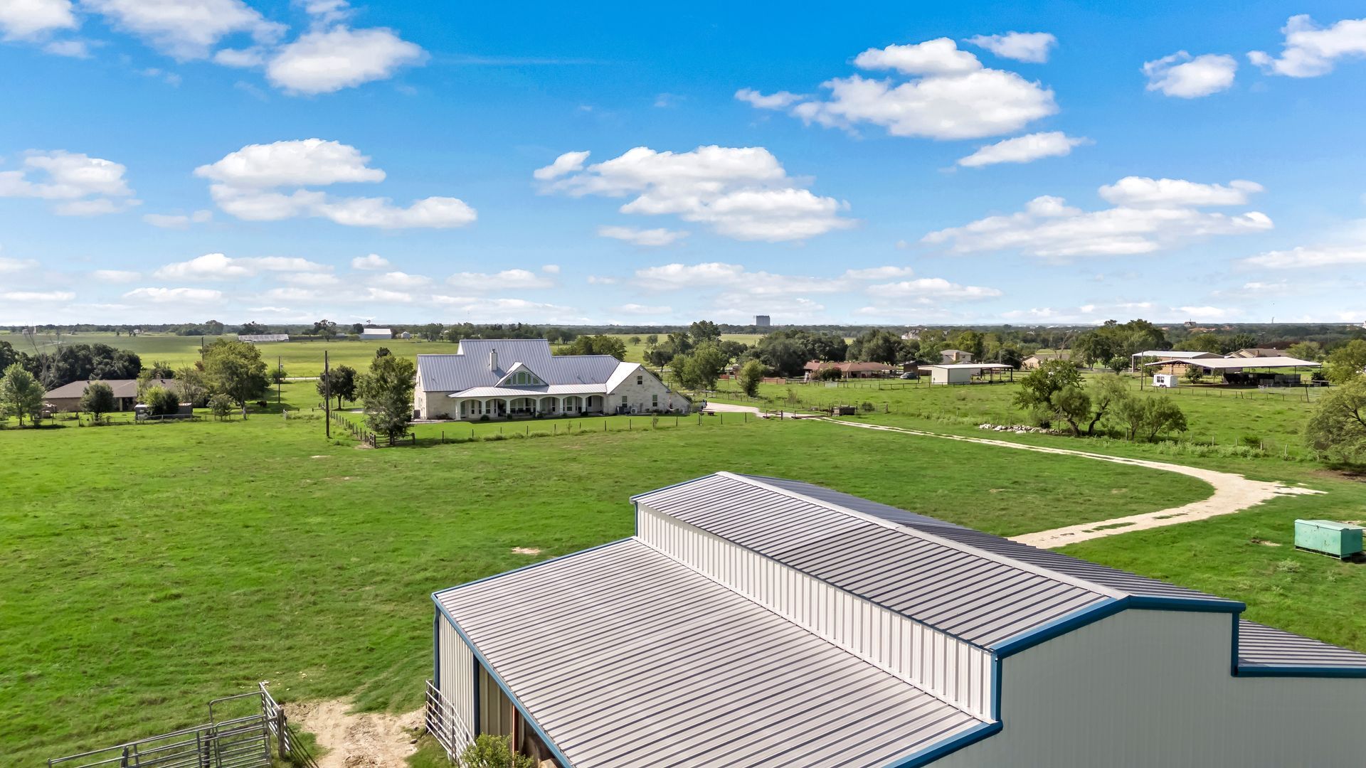 An aerial view of a large barn in the middle of a grassy field.