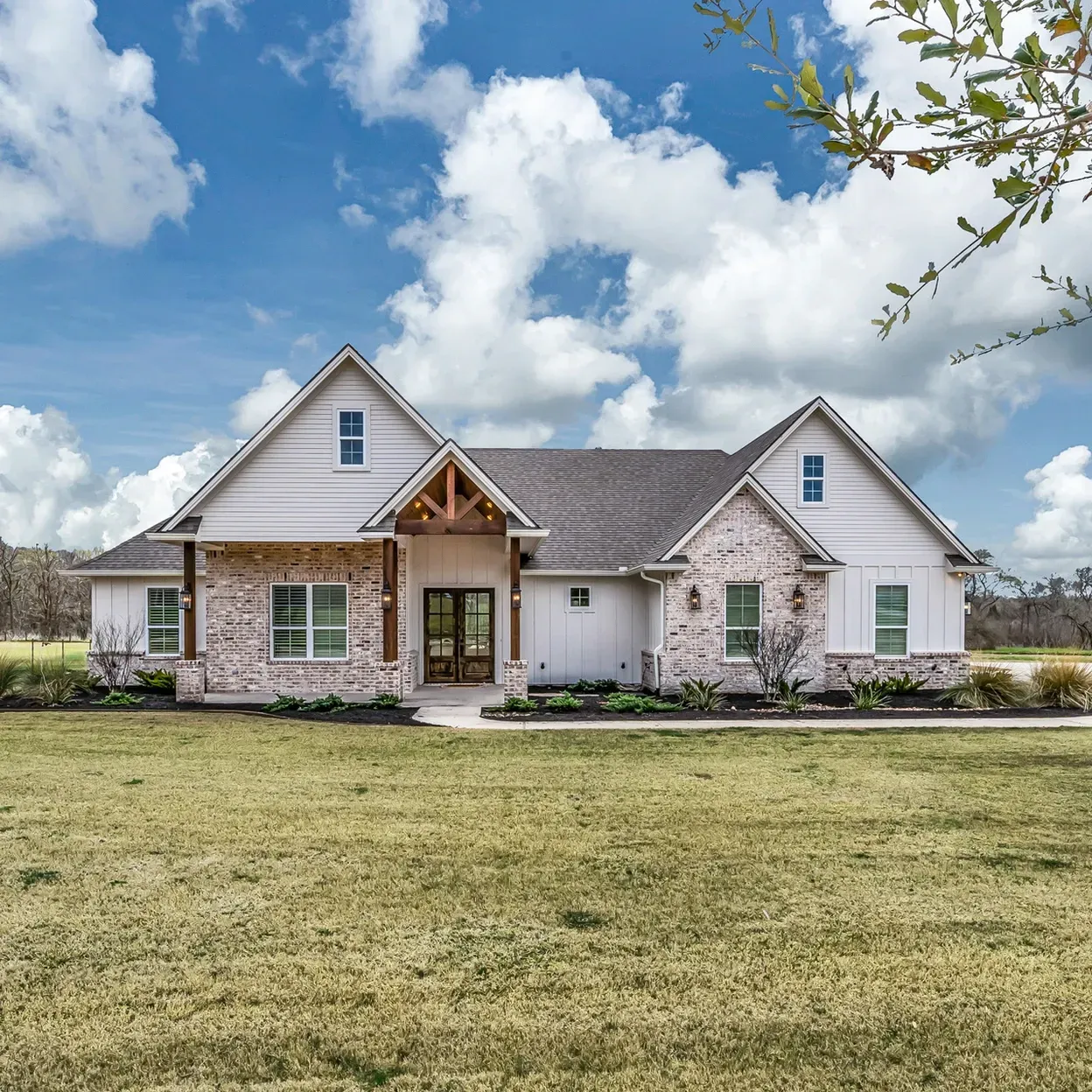 A large white house is sitting on top of a lush green field.