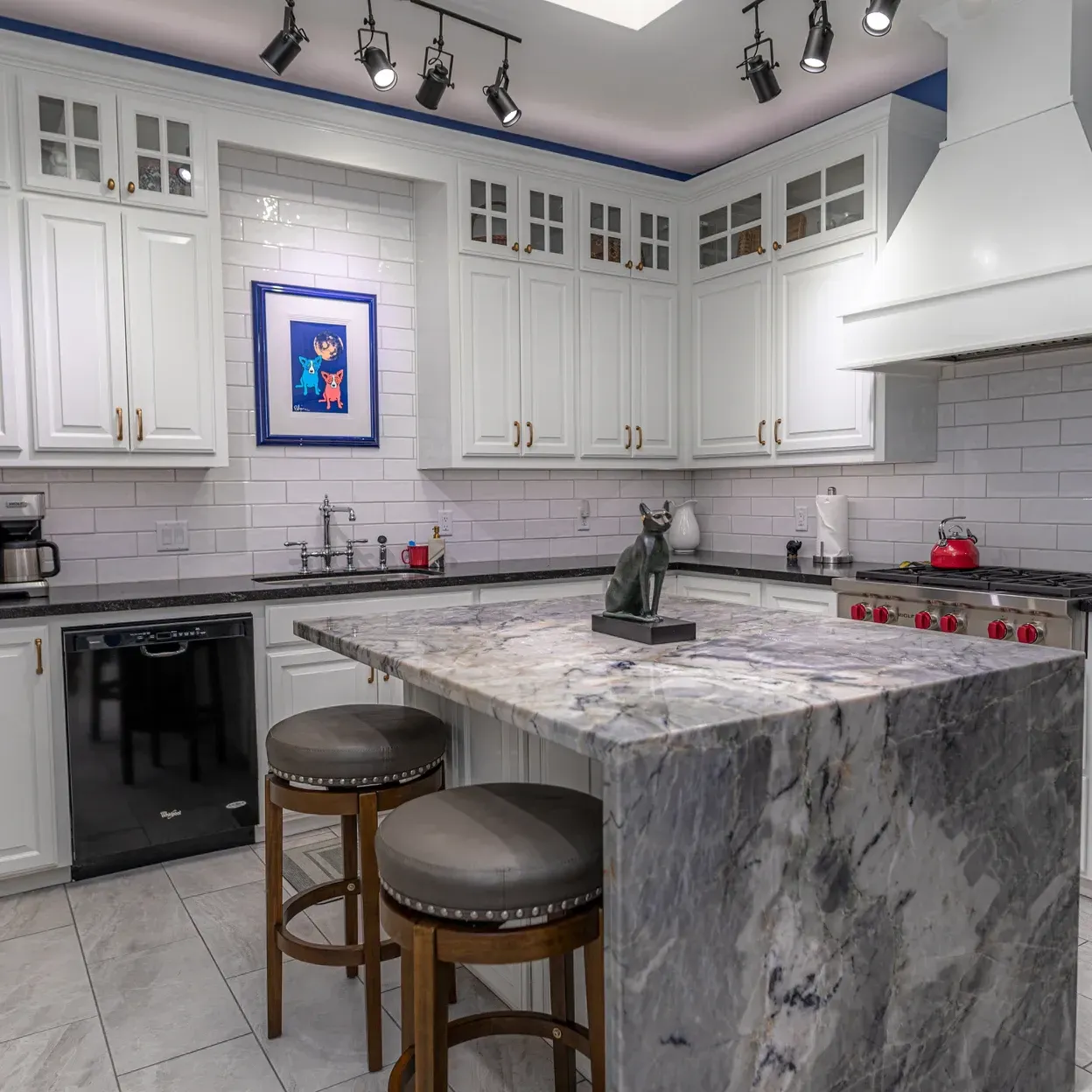 A kitchen with white cabinets and marble counter tops