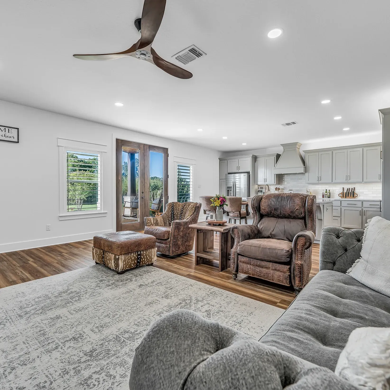 A living room with a couch , chairs , and a ceiling fan.
