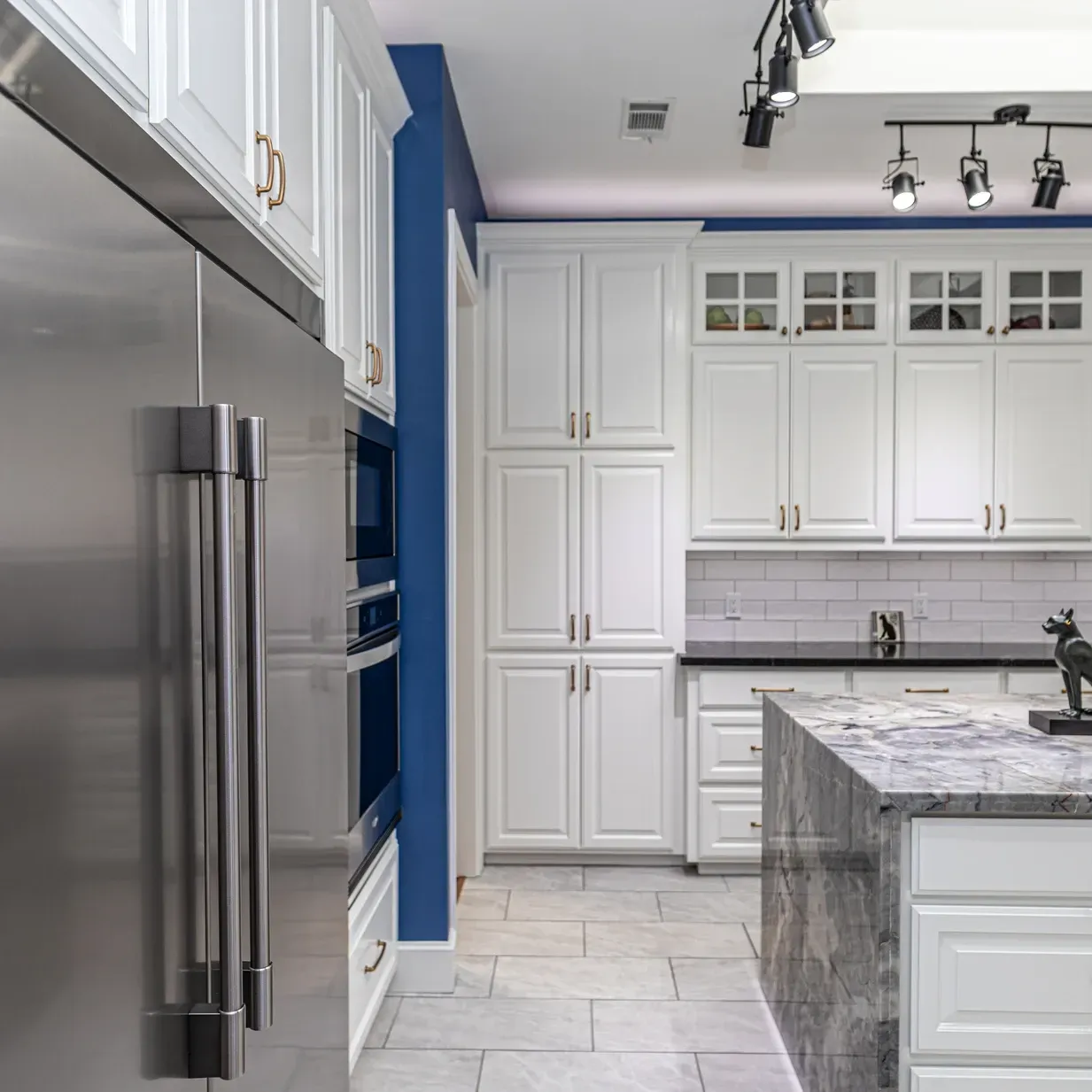 A kitchen with white cabinets and a stainless steel refrigerator.