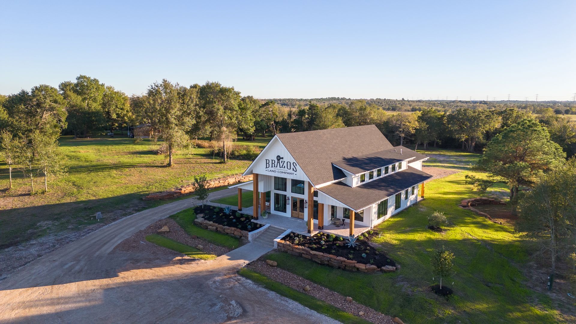 An aerial view of a large white house surrounded by trees and grass.
