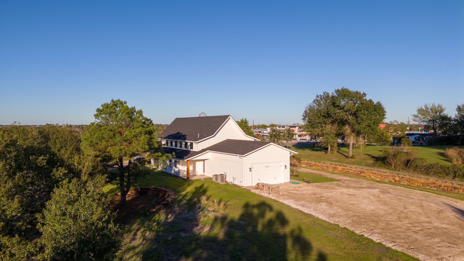 An aerial view of a house with a garage and trees in the background.