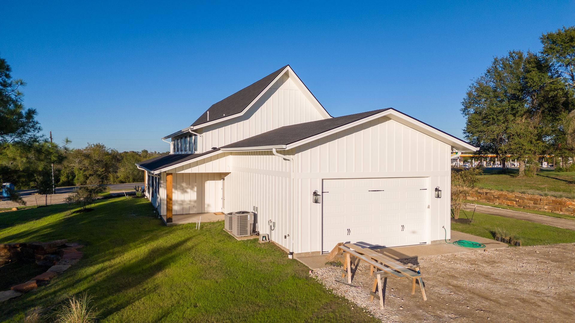 A white house with a garage in the backyard.