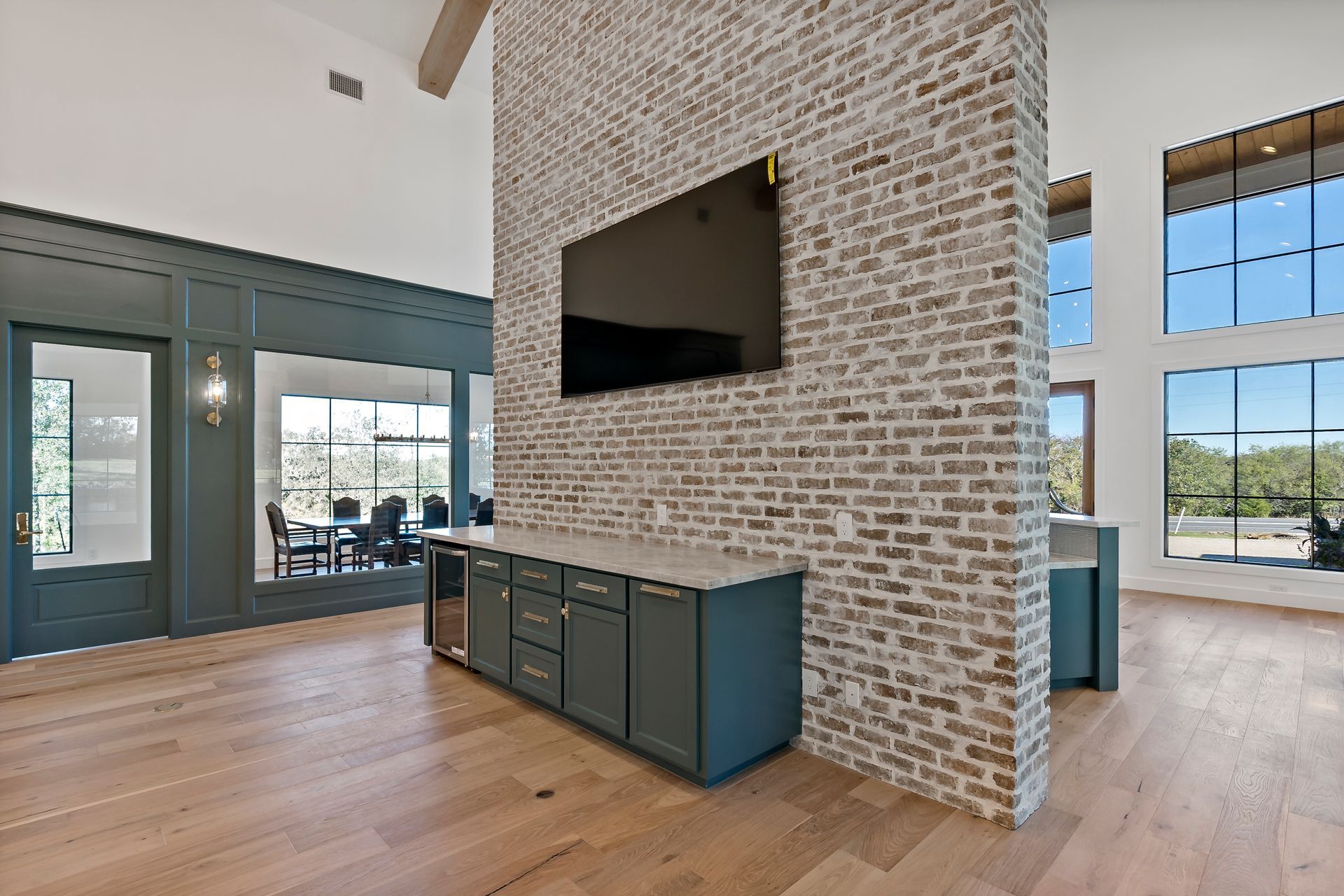 A living room with a brick wall and a flat screen tv on the wall.