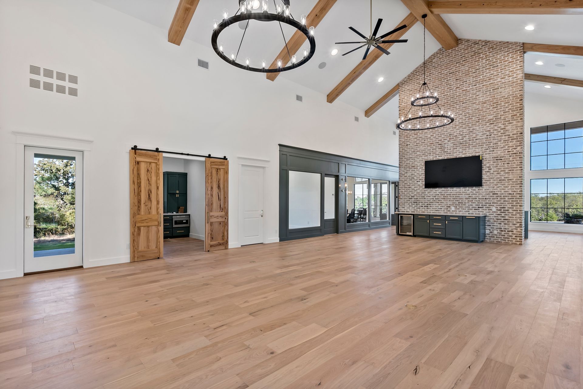 A large empty room with hardwood floors and a ceiling fan.