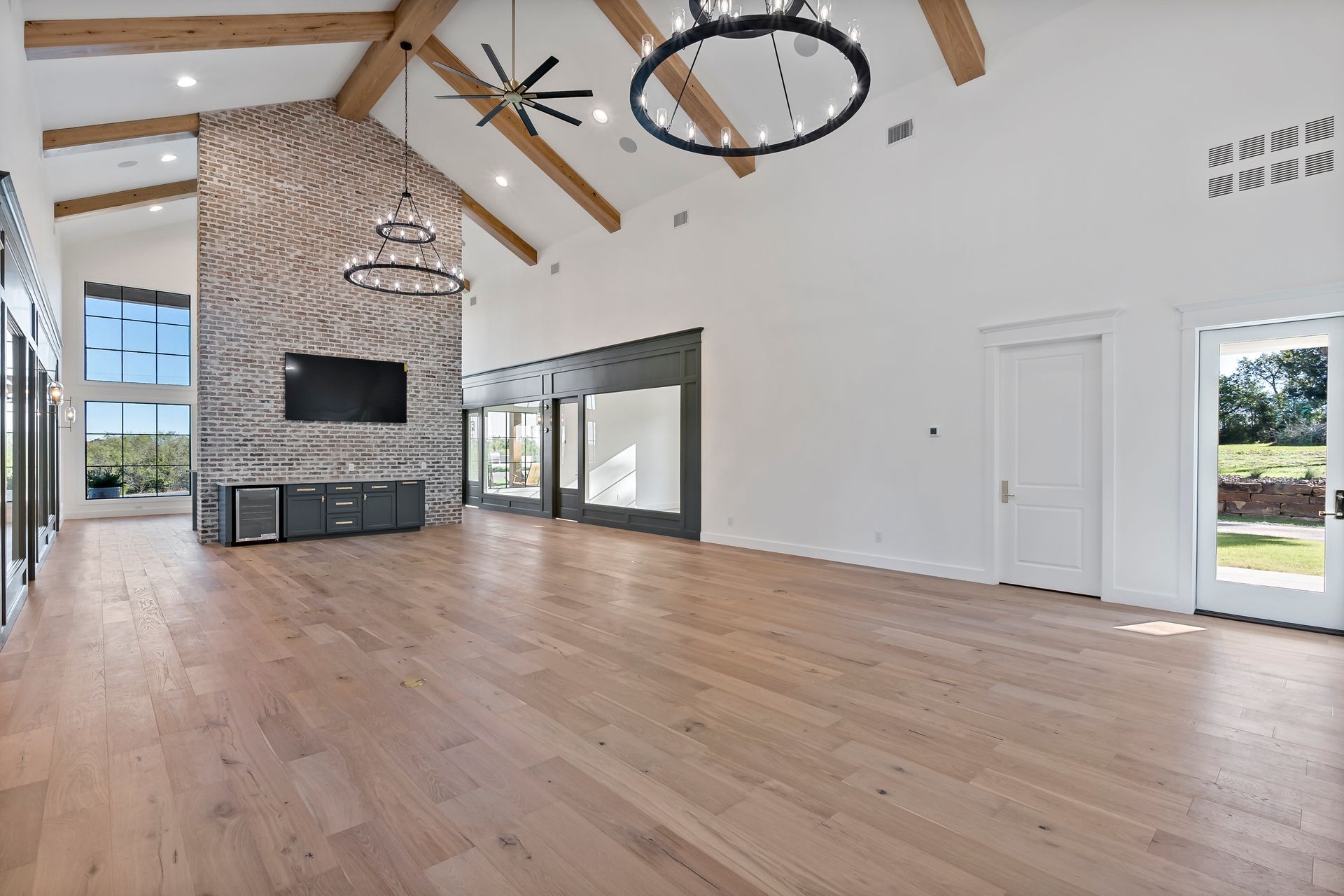 A large empty room with hardwood floors and a brick fireplace.