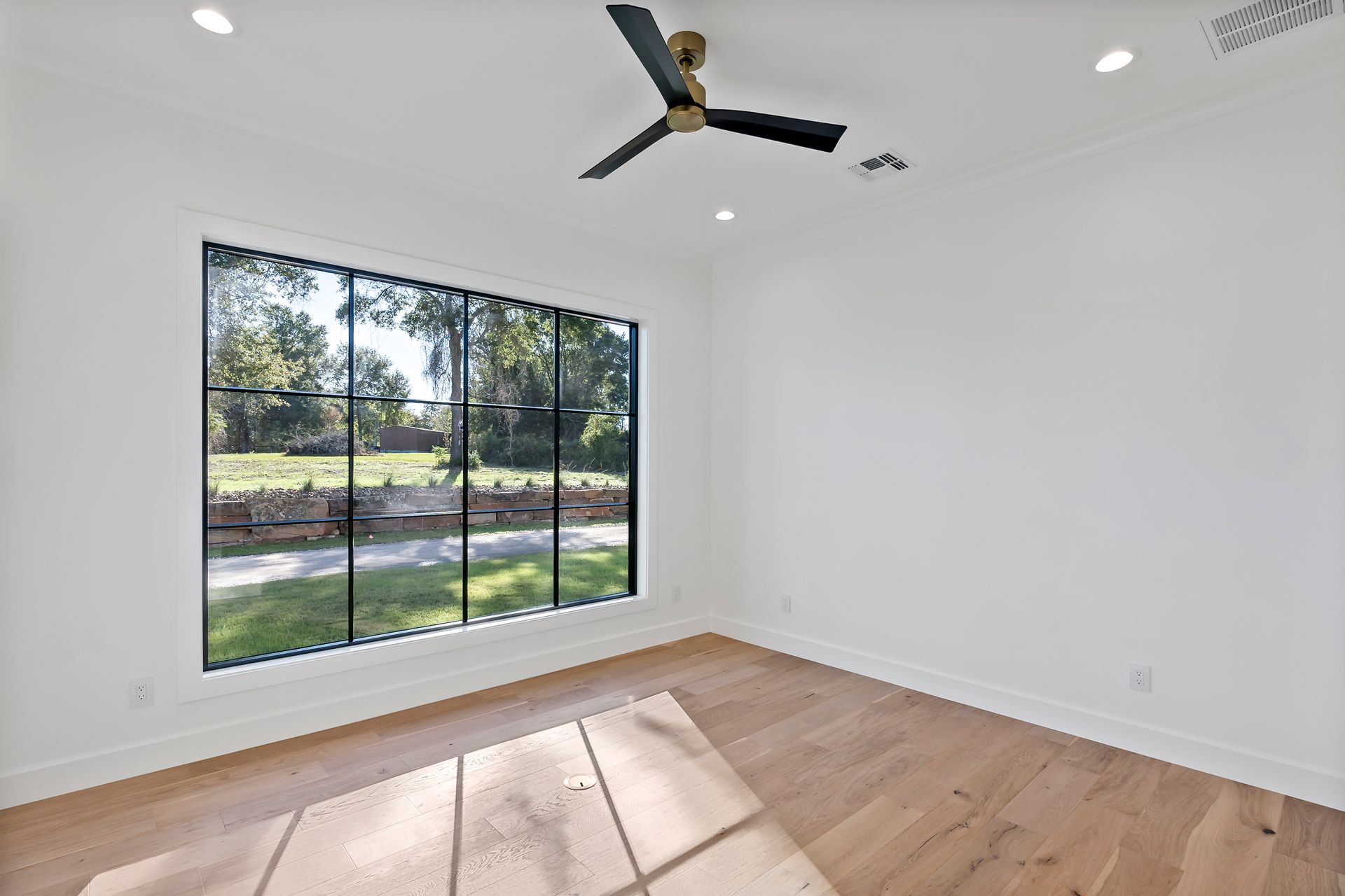 There is a ceiling fan in the room with a lot of windows.