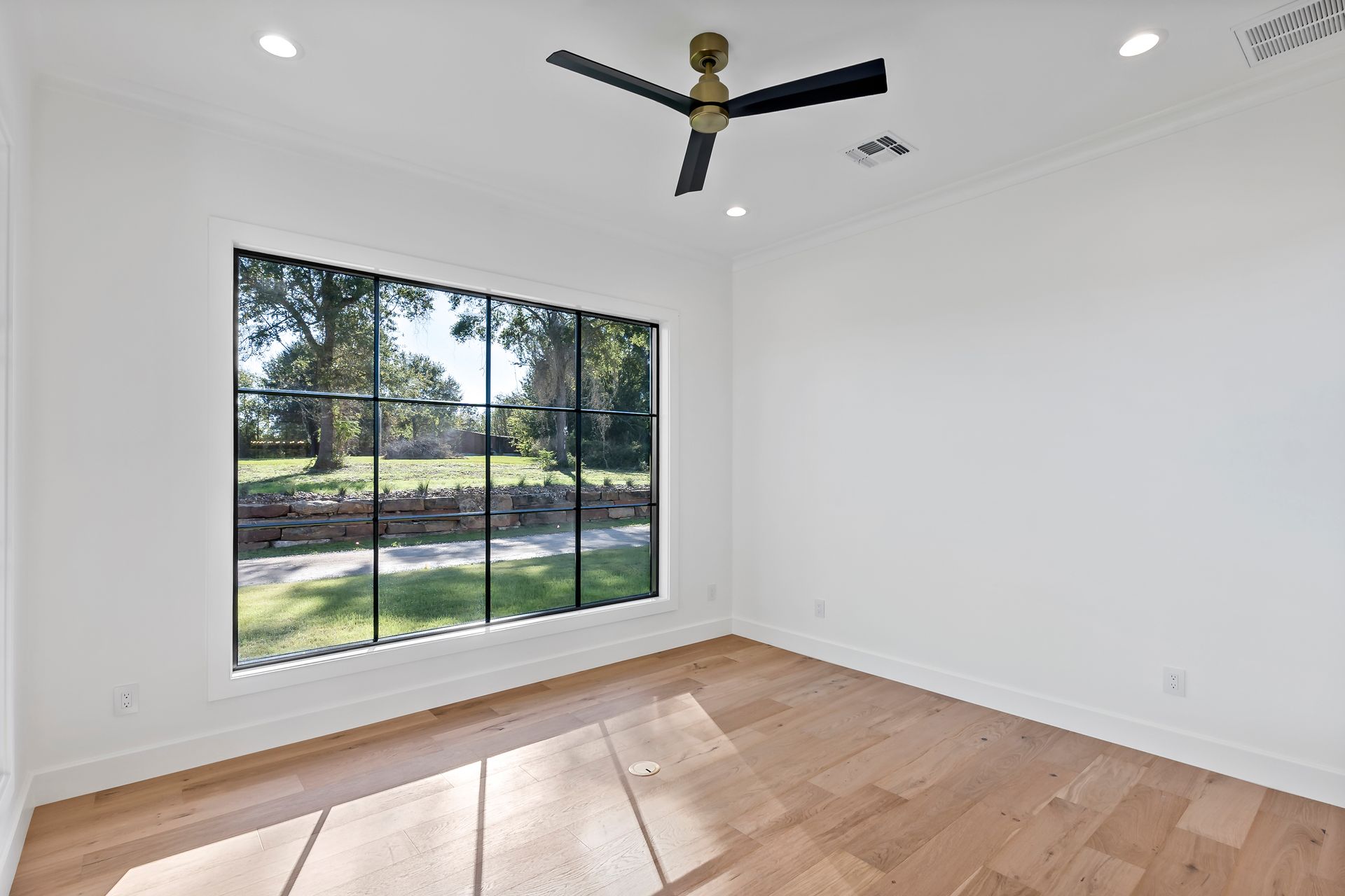 An empty room with a ceiling fan and a large window.