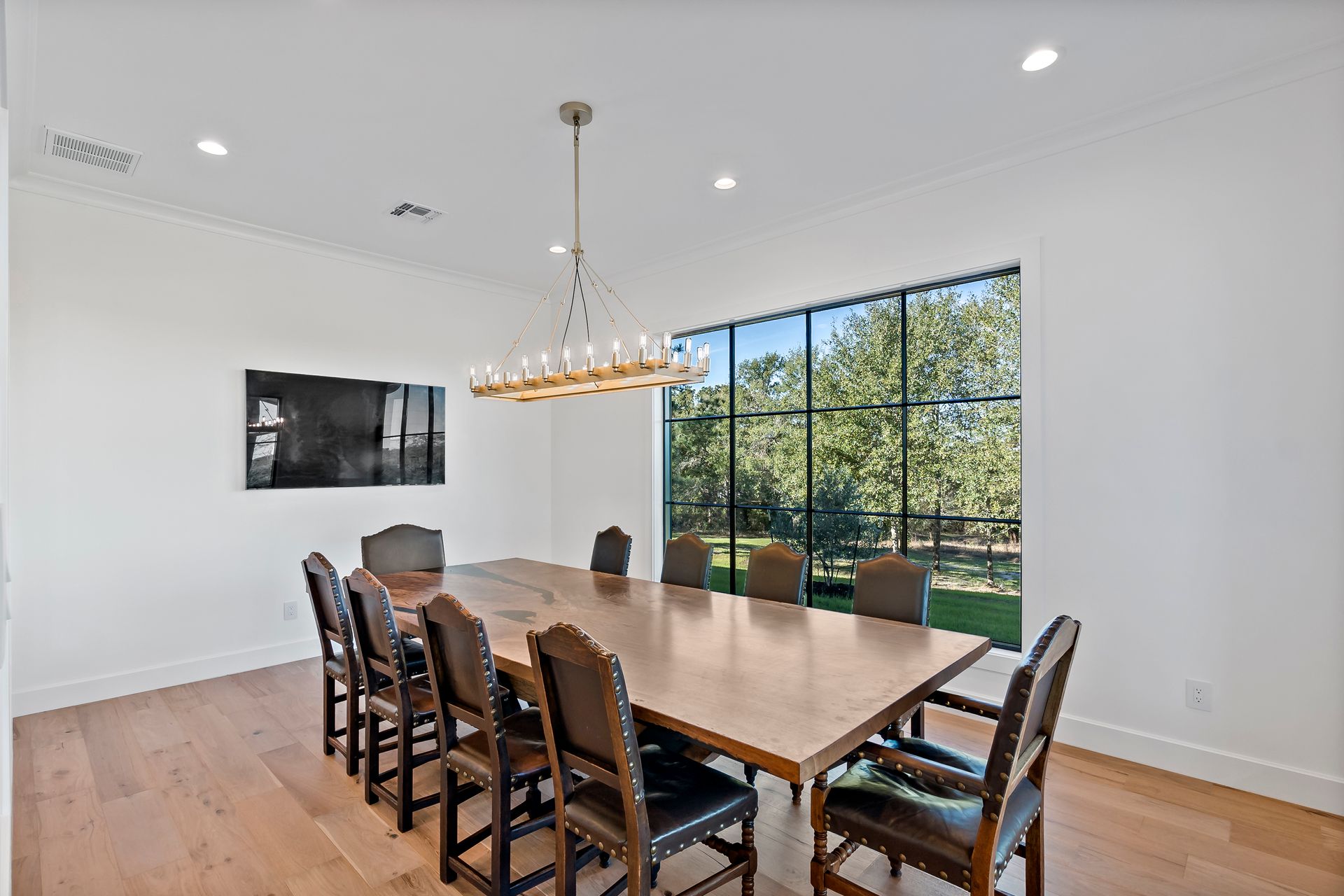 A dining room with a long table and chairs and a large window.
