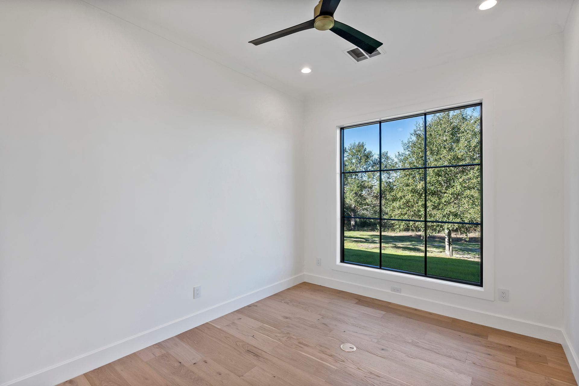 An empty room with a ceiling fan and a large window.