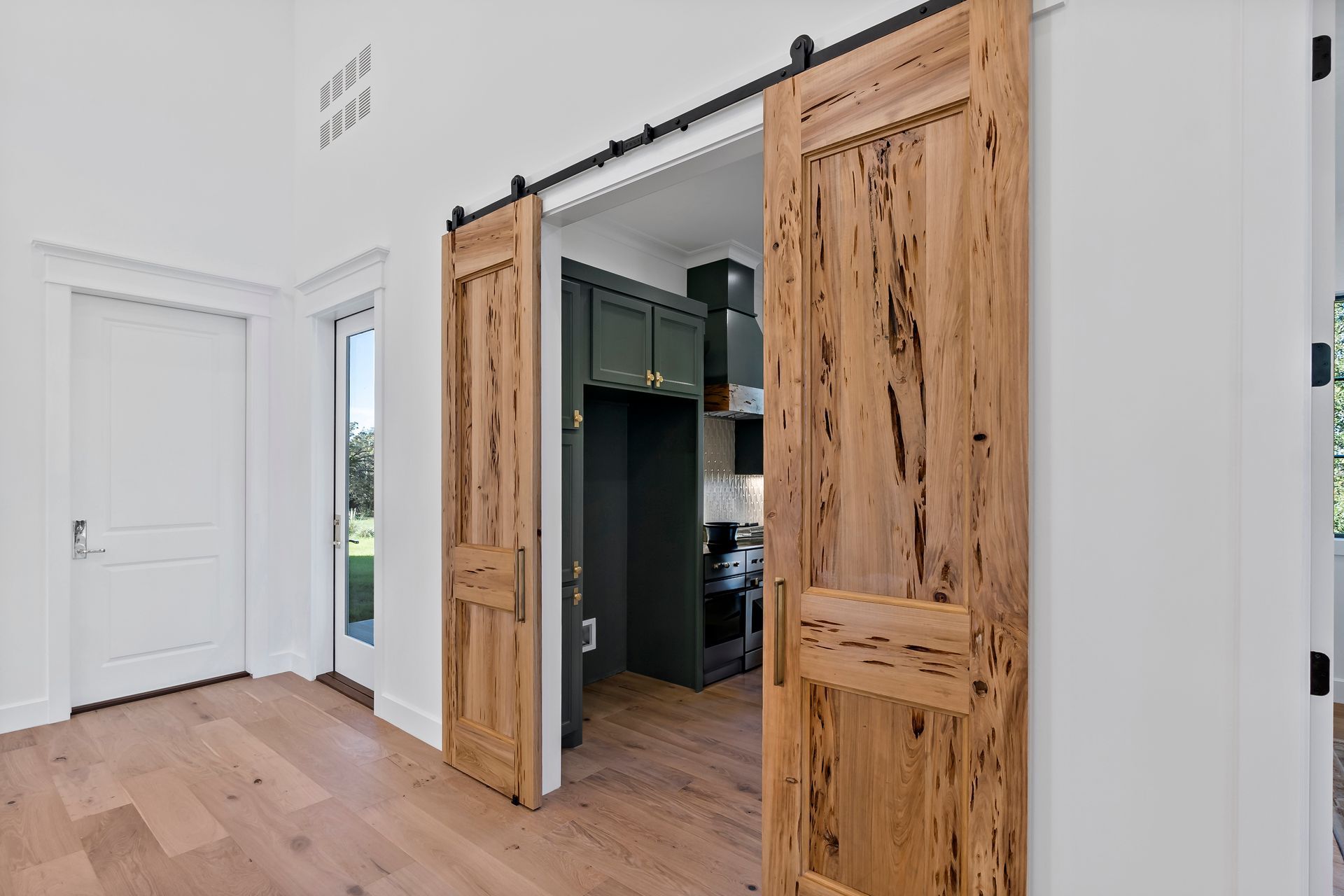 A kitchen with sliding barn doors leading to it.