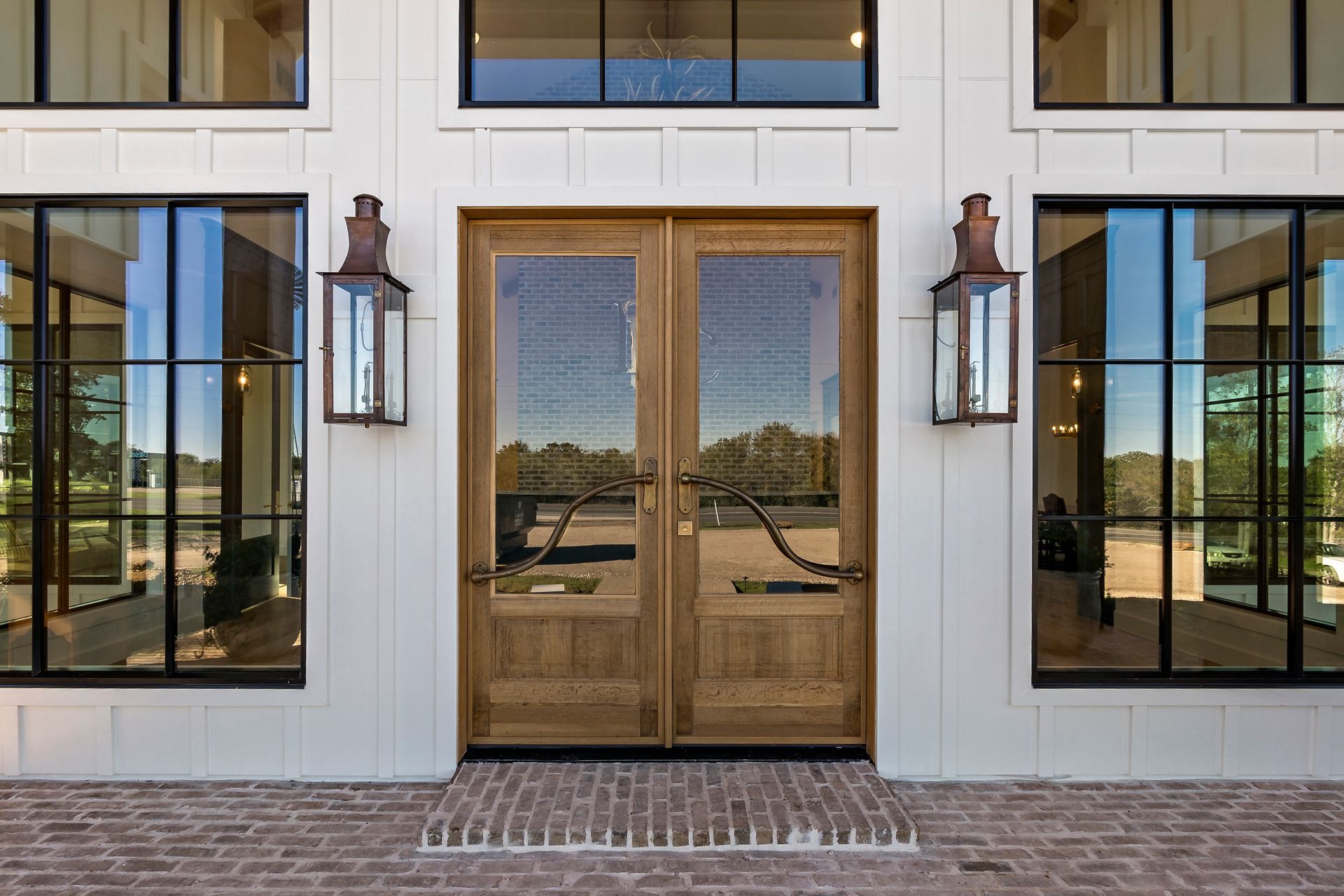 The front of a white house with a wooden door and a lot of windows.