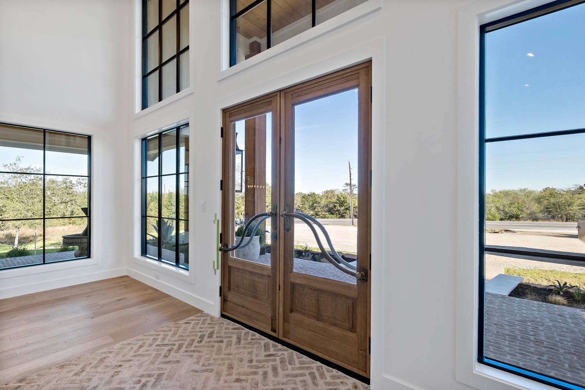 A living room with a lot of windows and a wooden door.