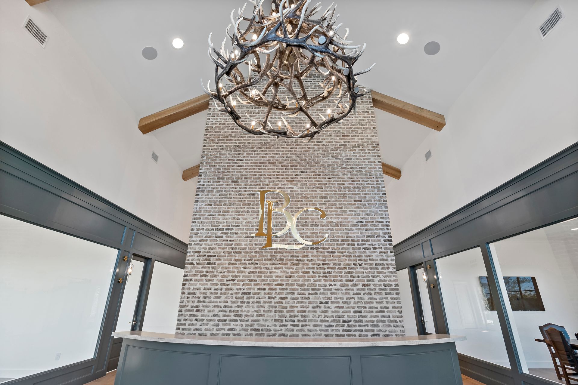 A large chandelier is hanging from the ceiling above a brick wall.