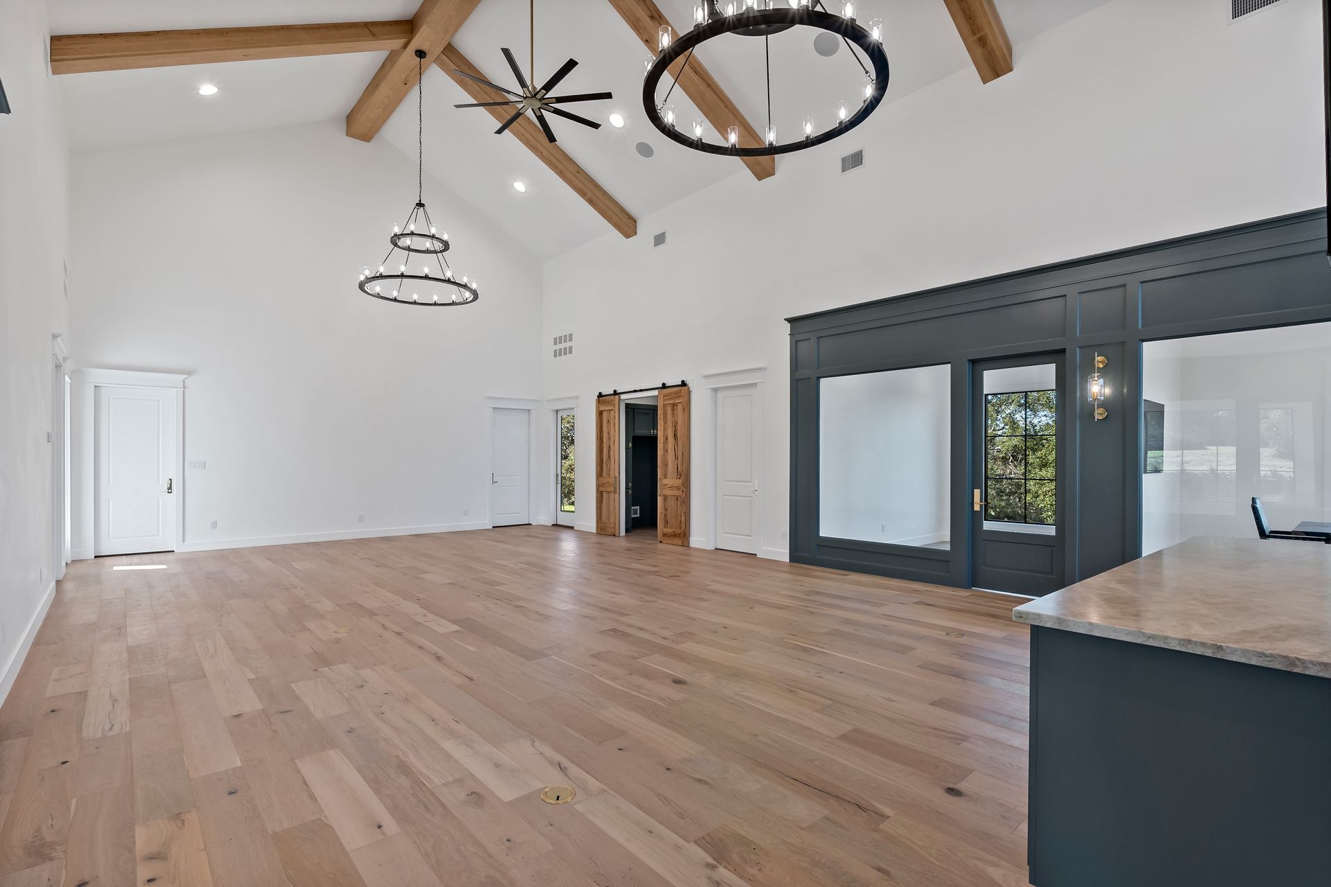 A large empty room with hardwood floors and a ceiling fan.