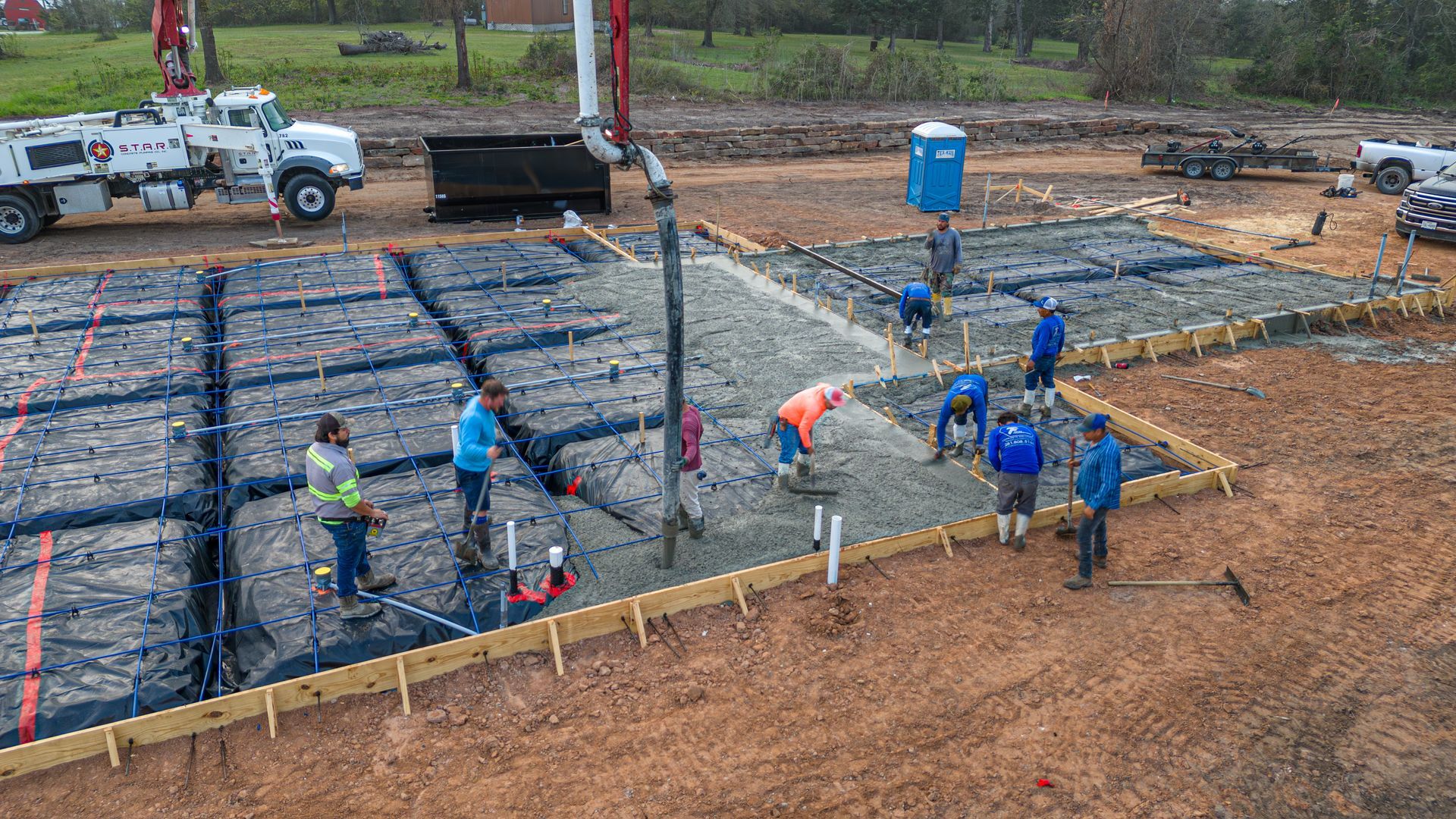 A group of construction workers are working on a concrete foundation.