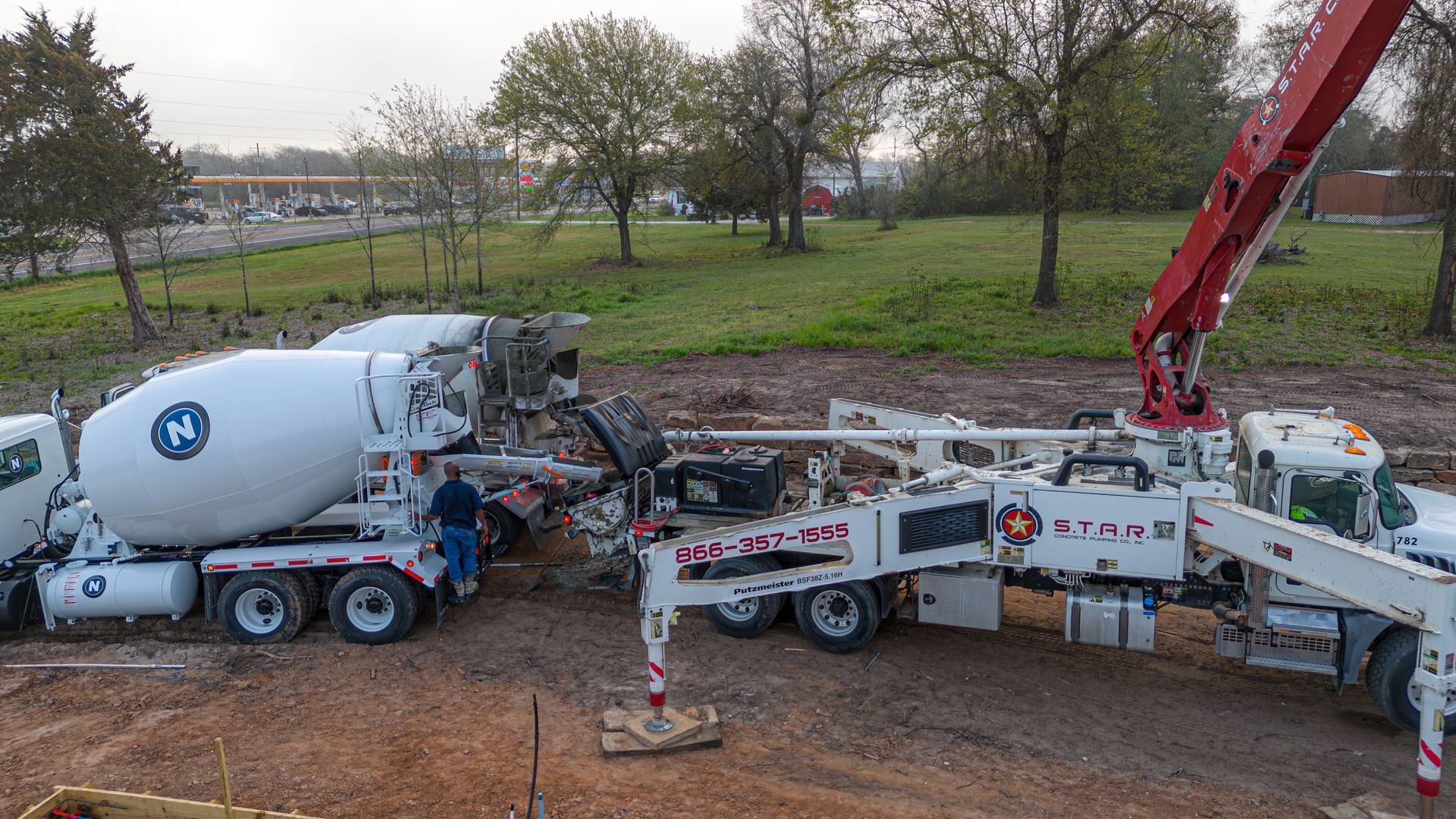 A concrete mixer truck and a concrete pump truck are working on a construction site.