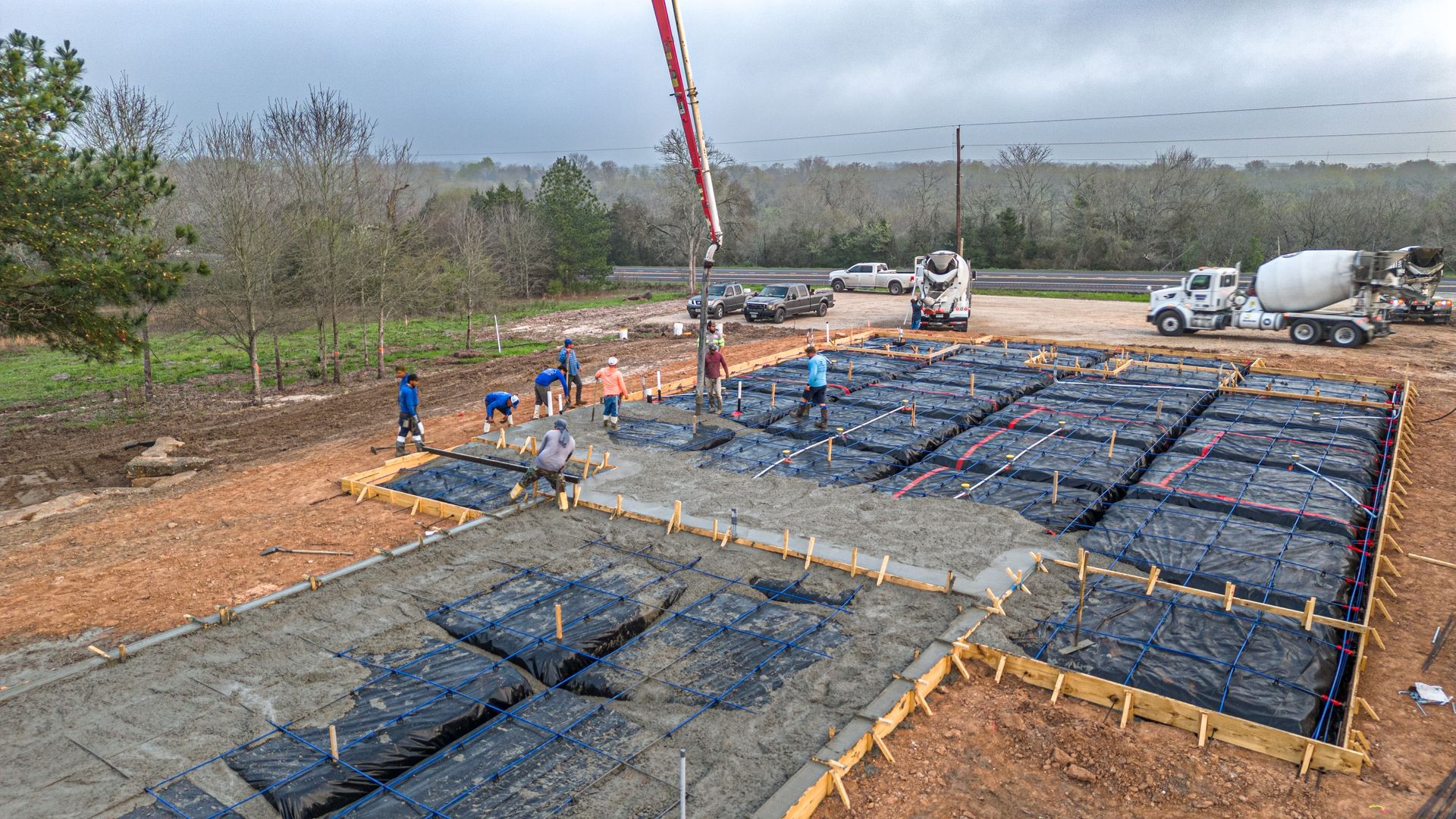 A crane is pouring concrete into a foundation of a house.