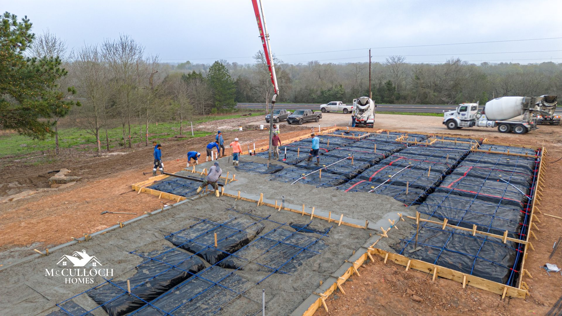 A crane is pouring concrete into a foundation of a house.
