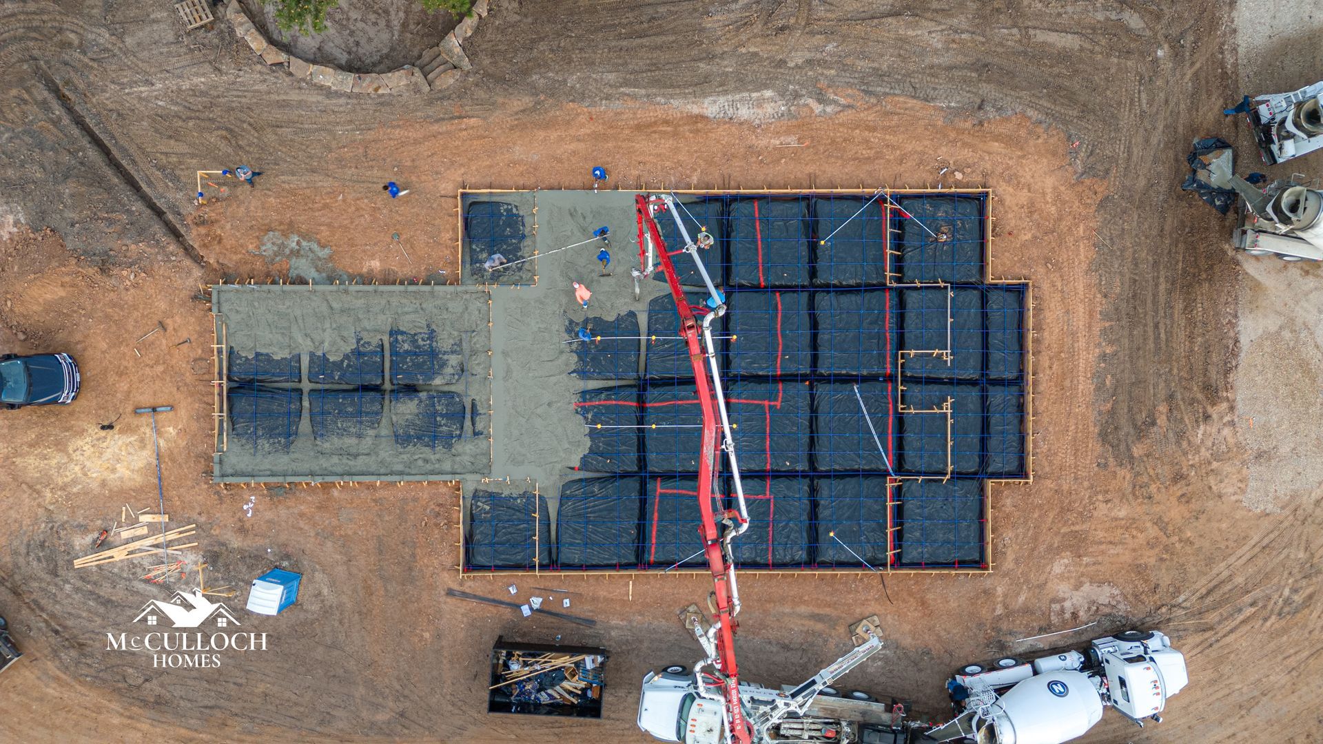 An aerial view of a construction site with a crane pumping concrete.