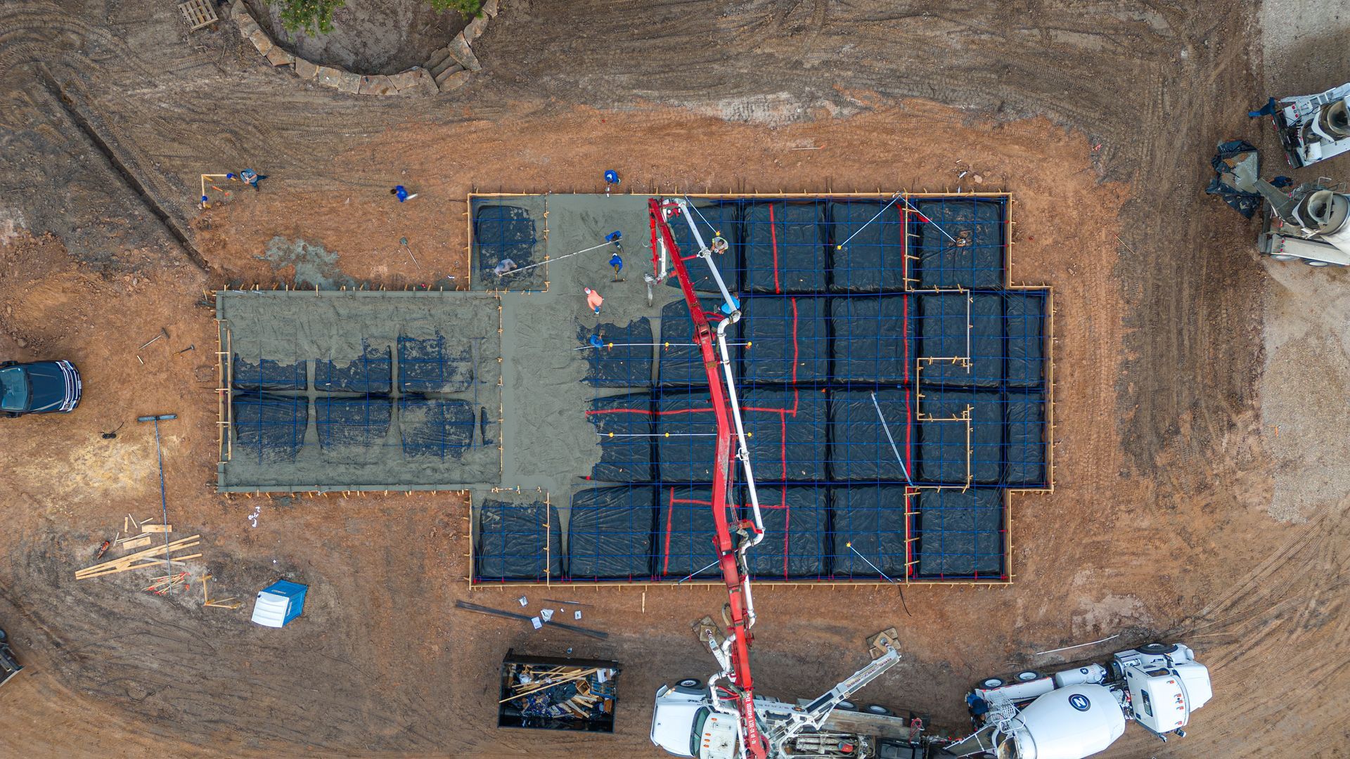An aerial view of a construction site with a crane pumping concrete.