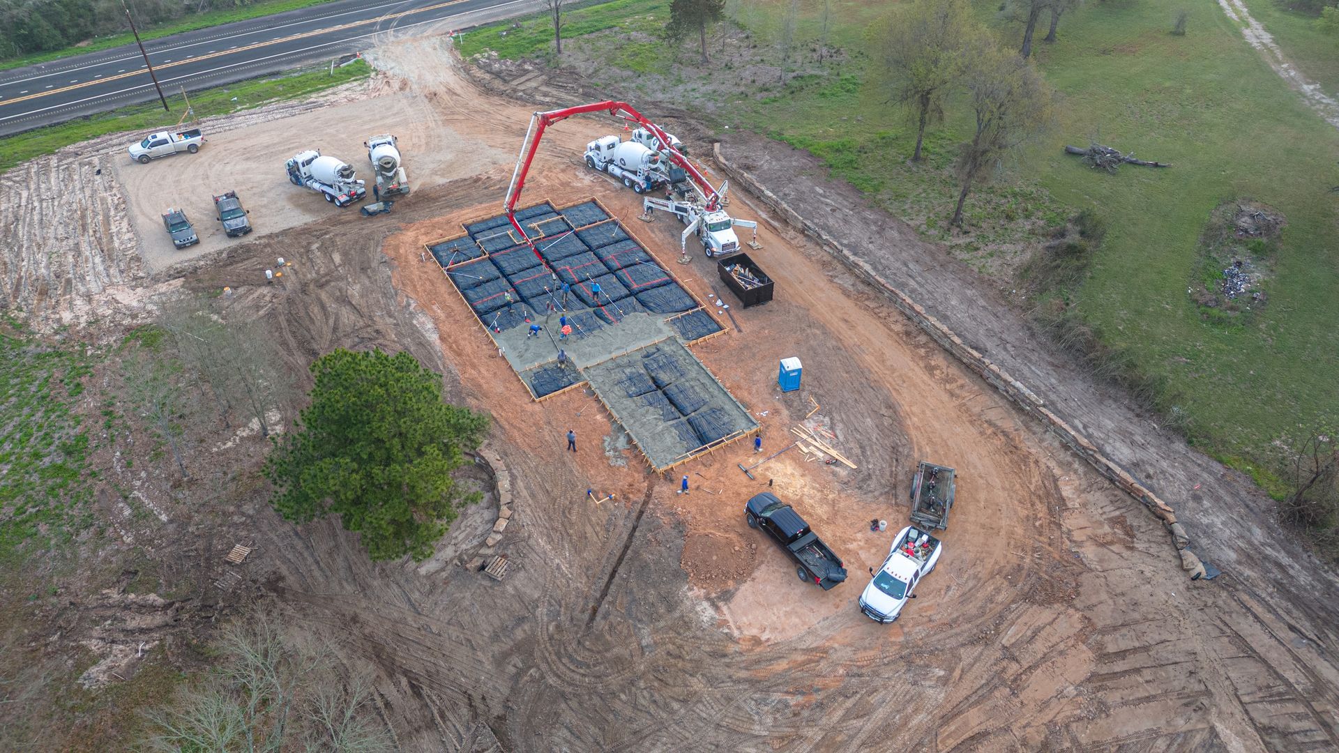 An aerial view of a construction site with trucks and a concrete pump.