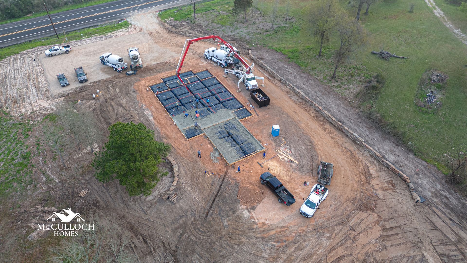An aerial view of a construction site with trucks and a concrete pump.