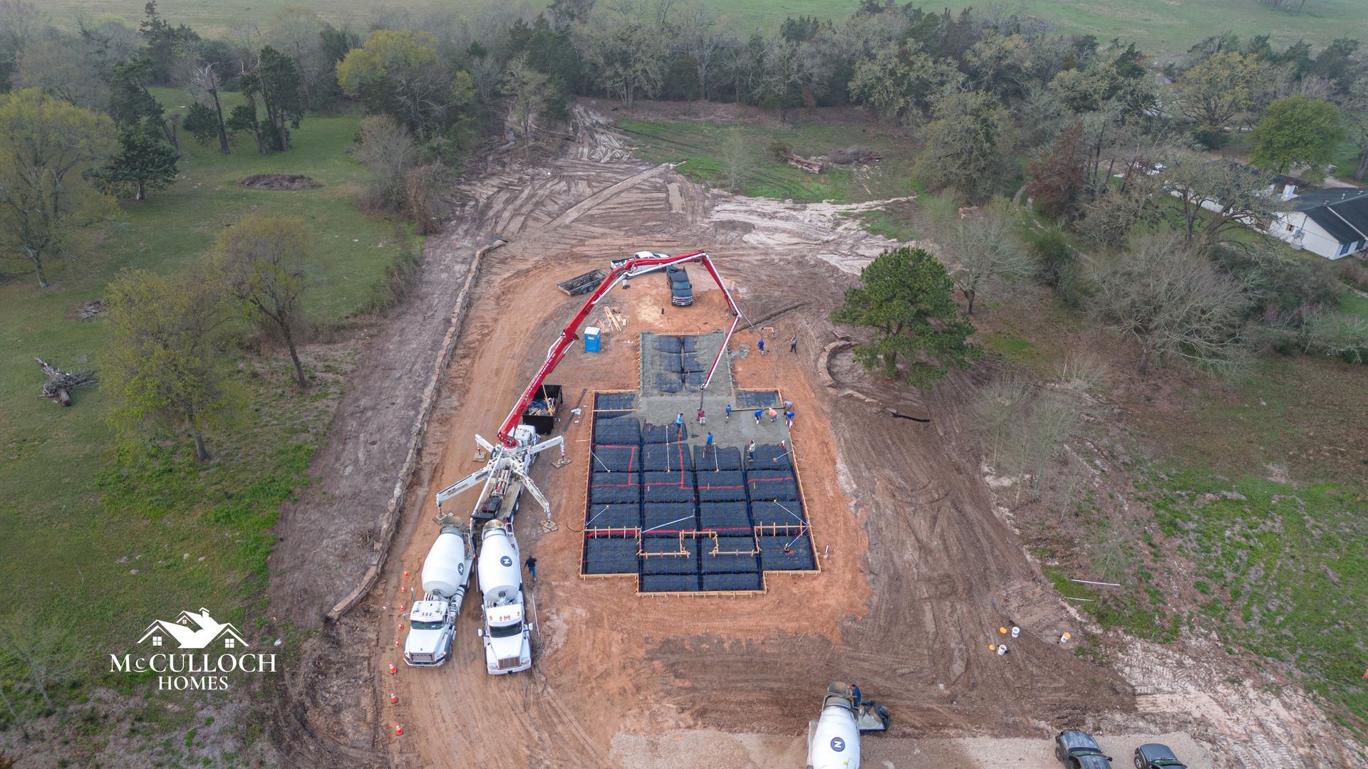 An aerial view of a construction site with trucks pumping concrete.