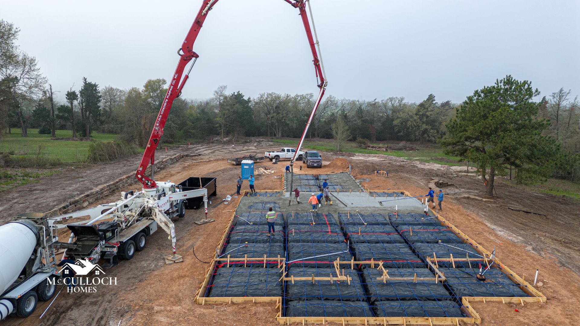 A concrete pump is pouring concrete into a foundation of a house.