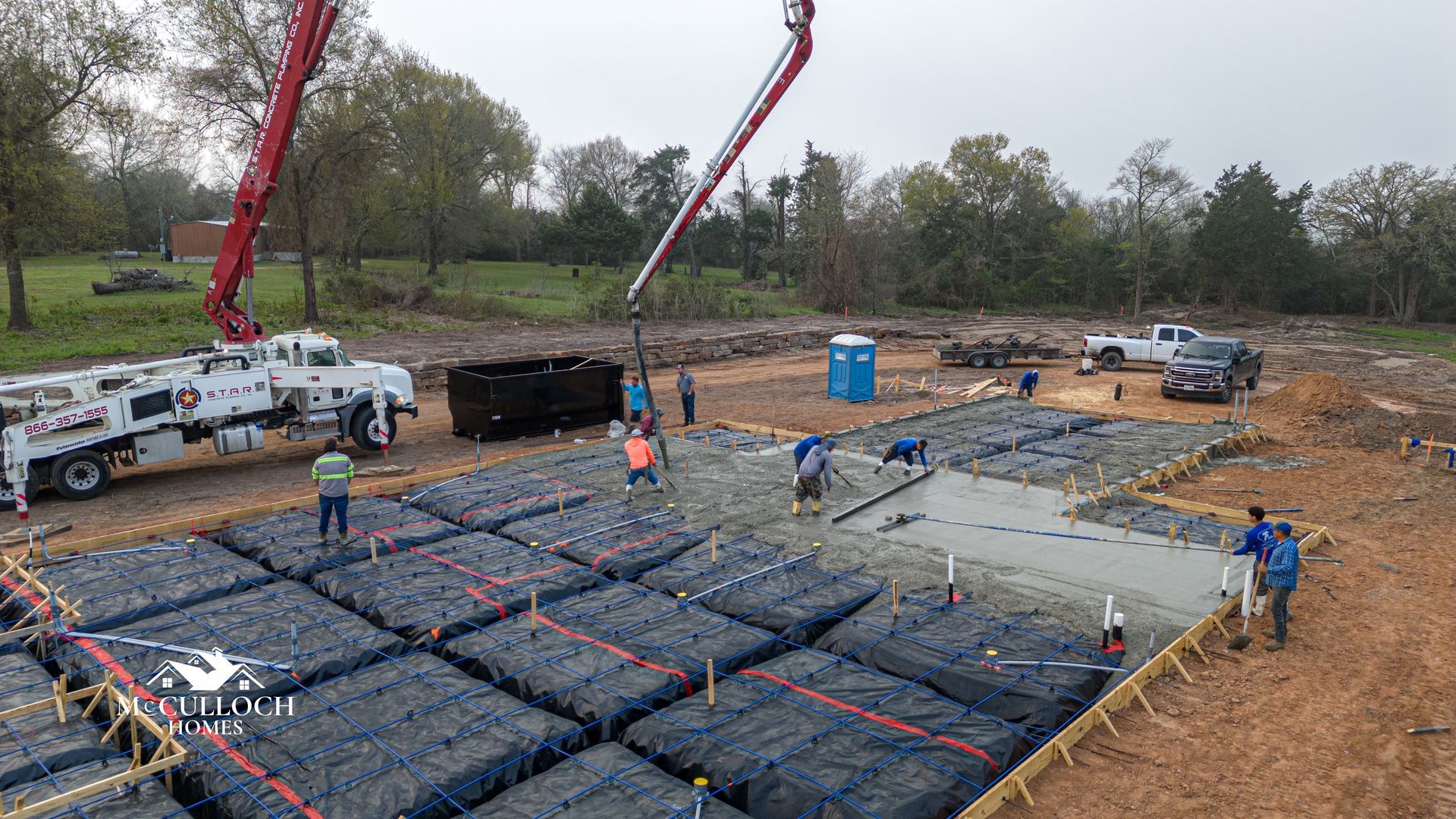 An aerial view of a construction site with a crane pouring concrete.