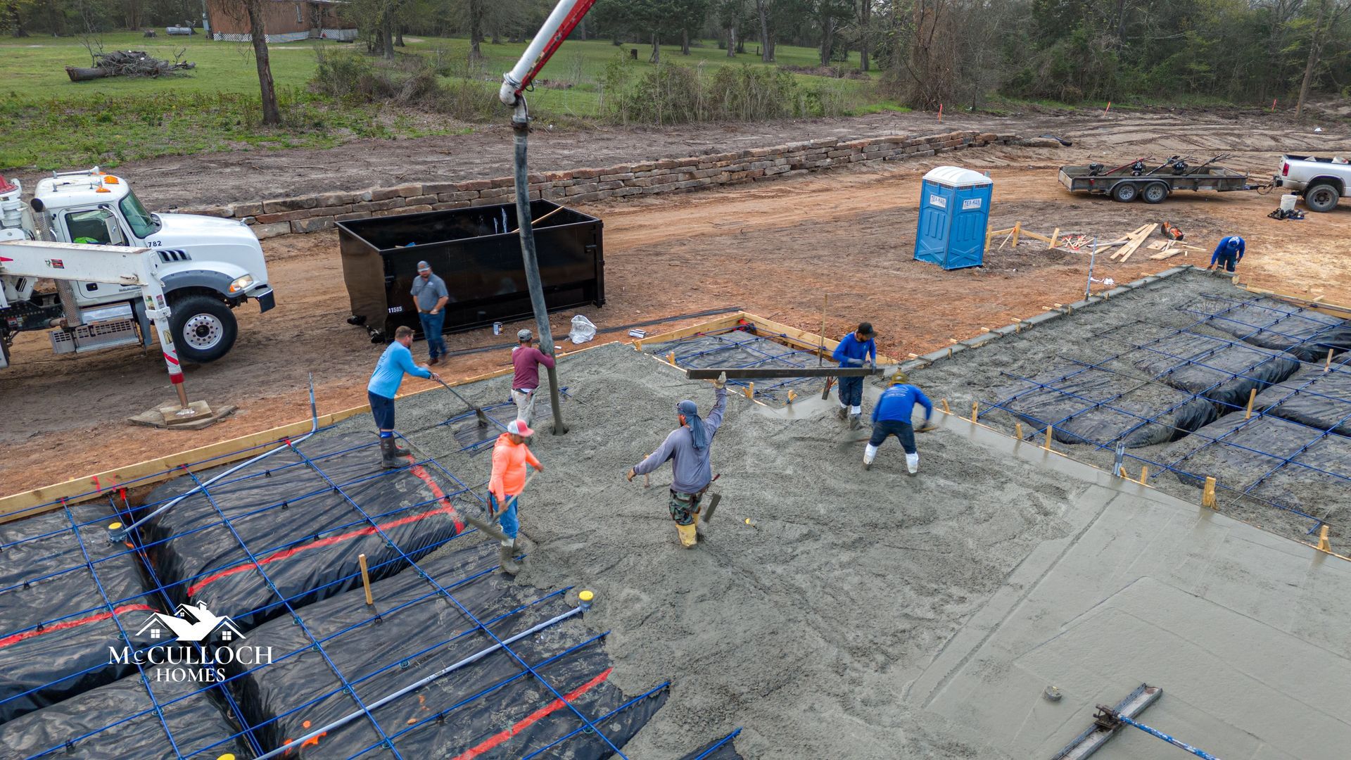 A group of construction workers are pouring concrete on a construction site.