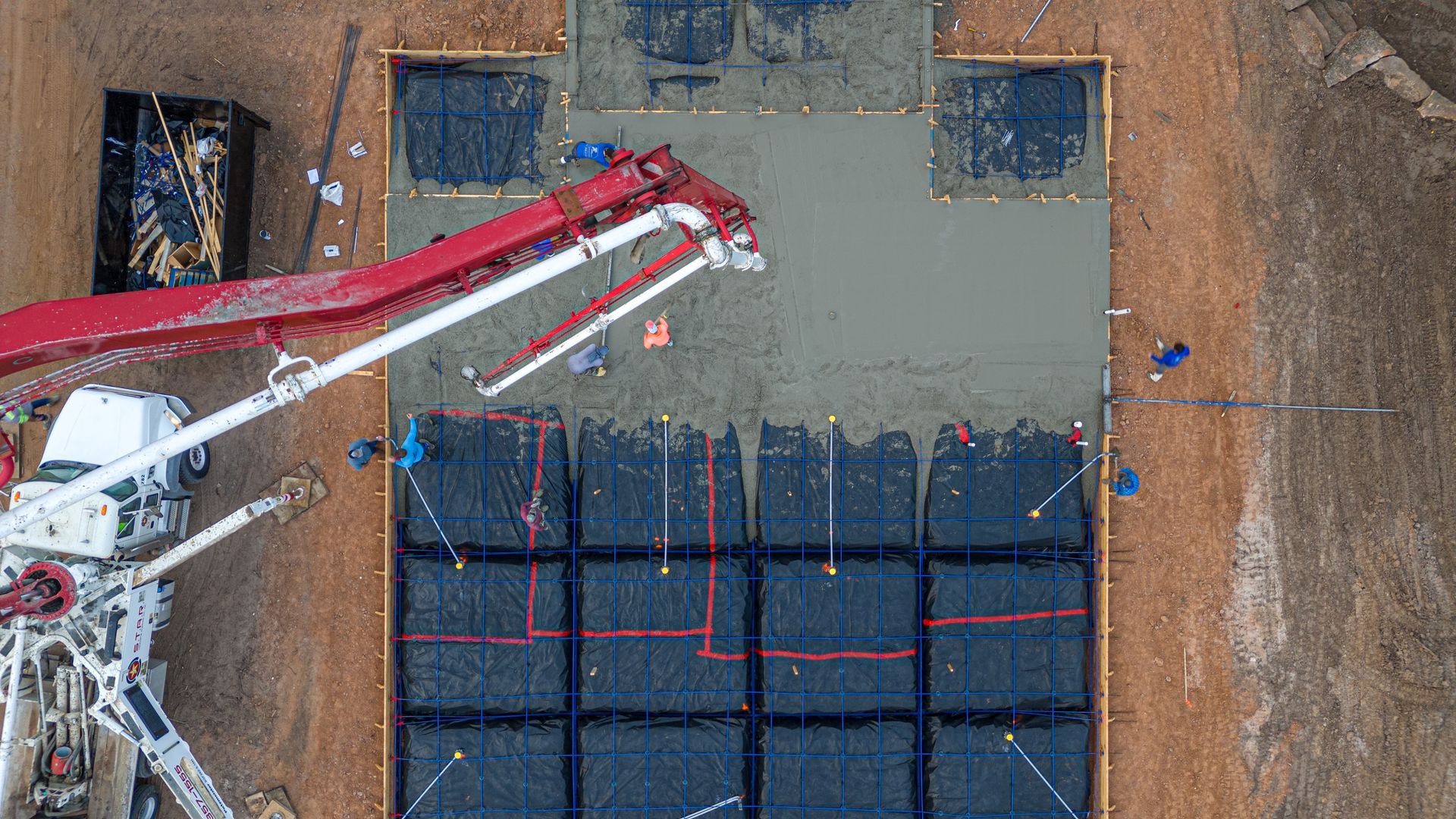 An aerial view of a crane pouring concrete on a construction site.