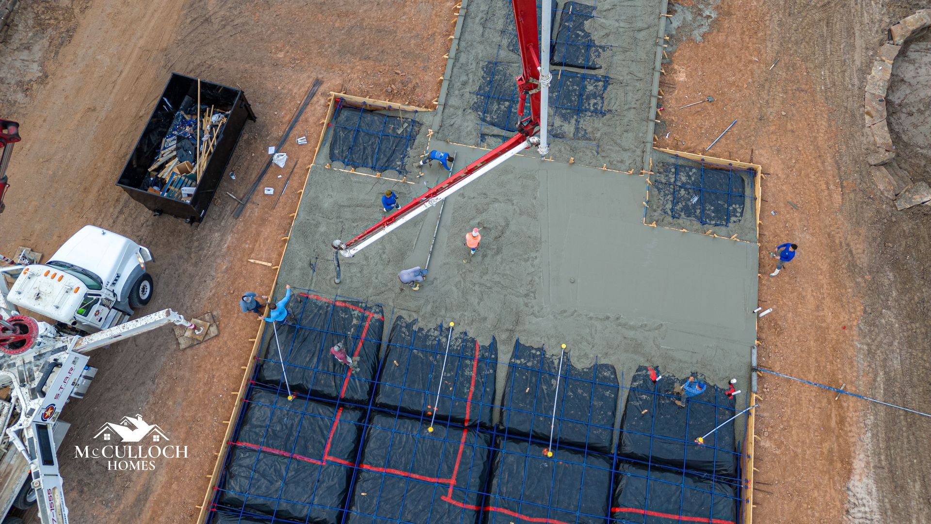 An aerial view of a concrete pump pouring concrete on a construction site.