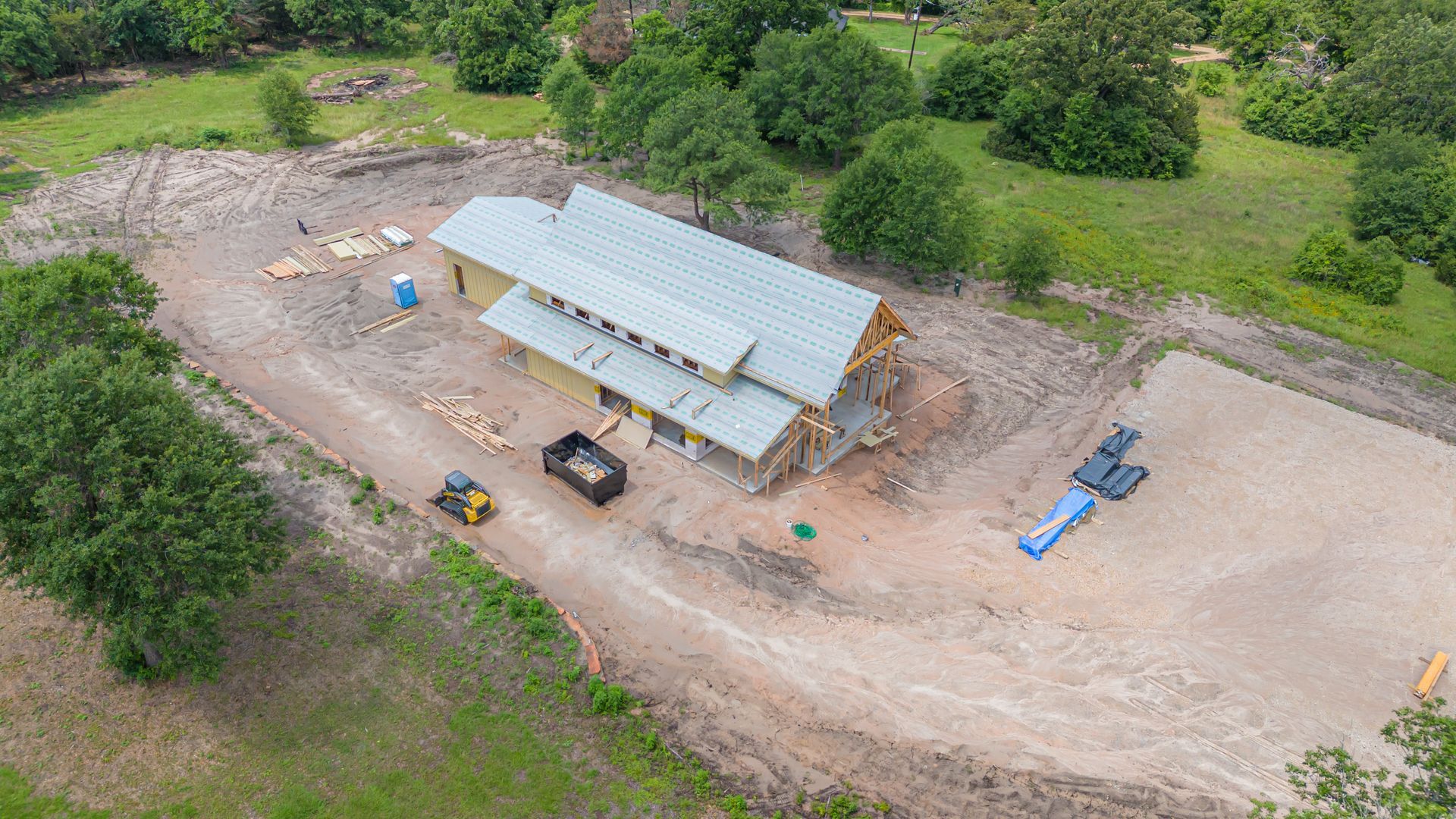 An aerial view of a house under construction in the middle of a field.