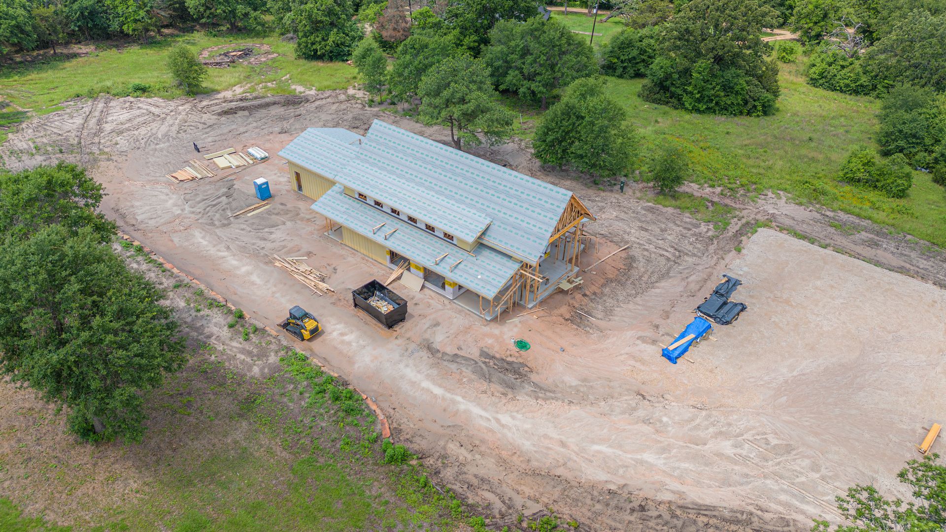 An aerial view of a house under construction in the middle of a field.