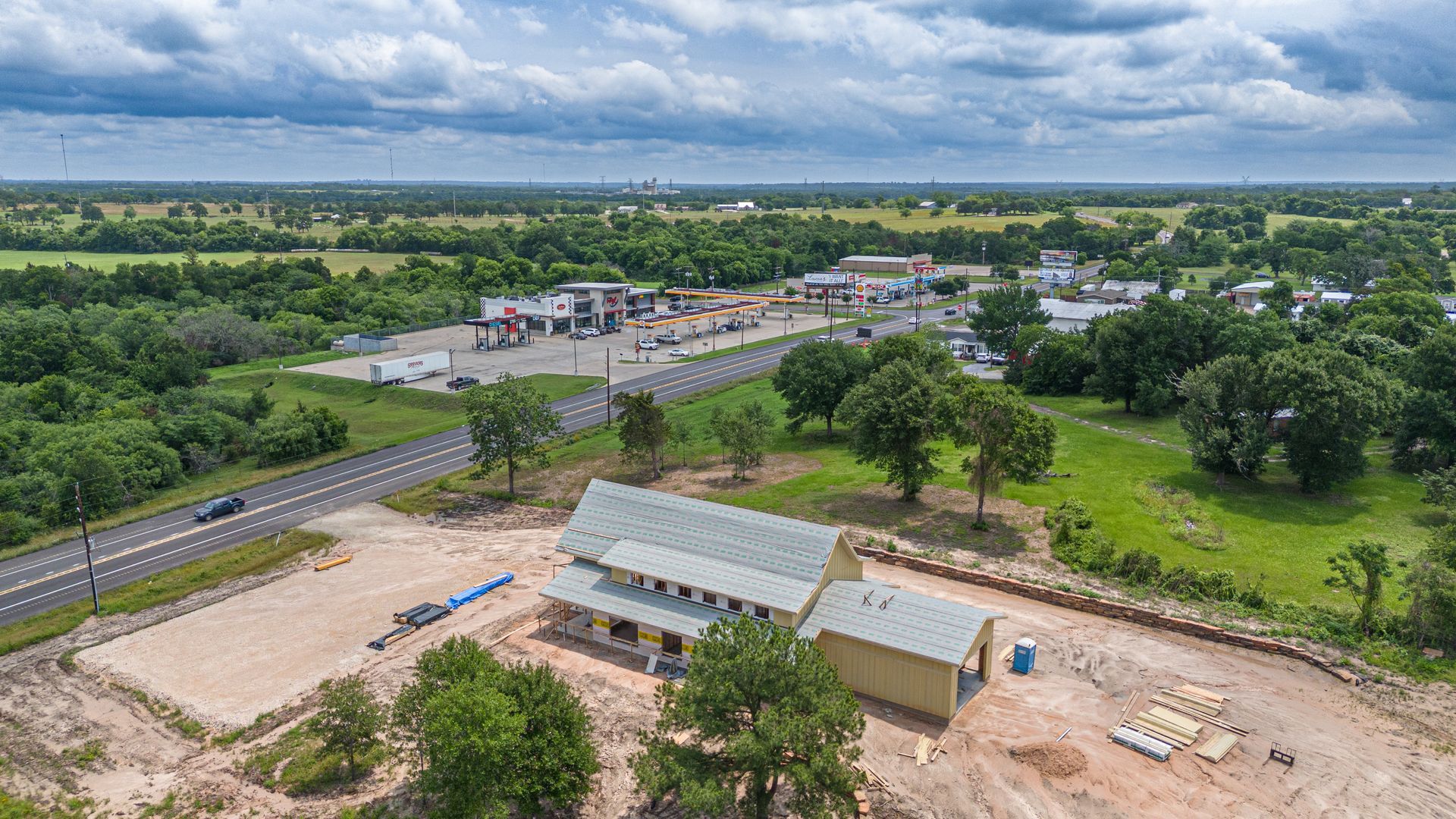 An aerial view of a building in the middle of a field next to a road.