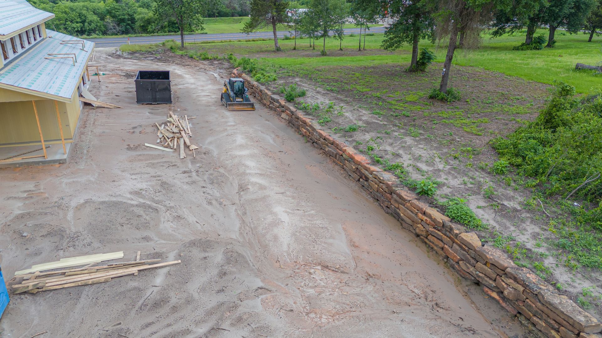 An aerial view of a dirt road leading to a house under construction.