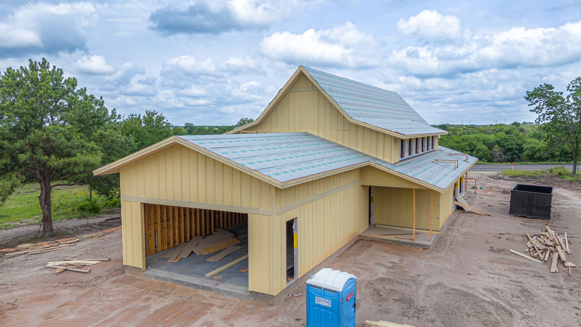 An aerial view of a house under construction with a blue toilet in front of it.