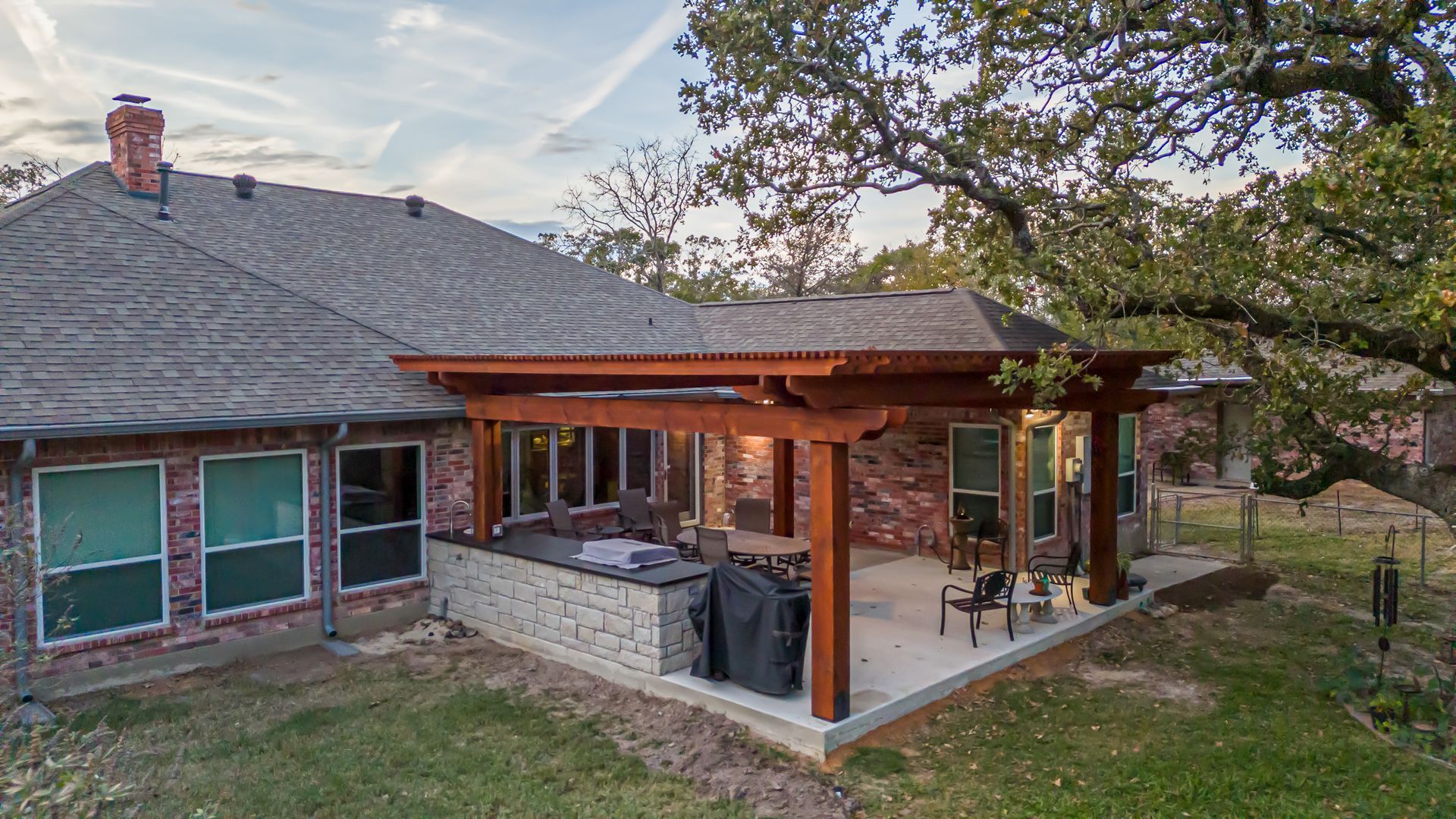 A brick house with a wooden pergola in the backyard.