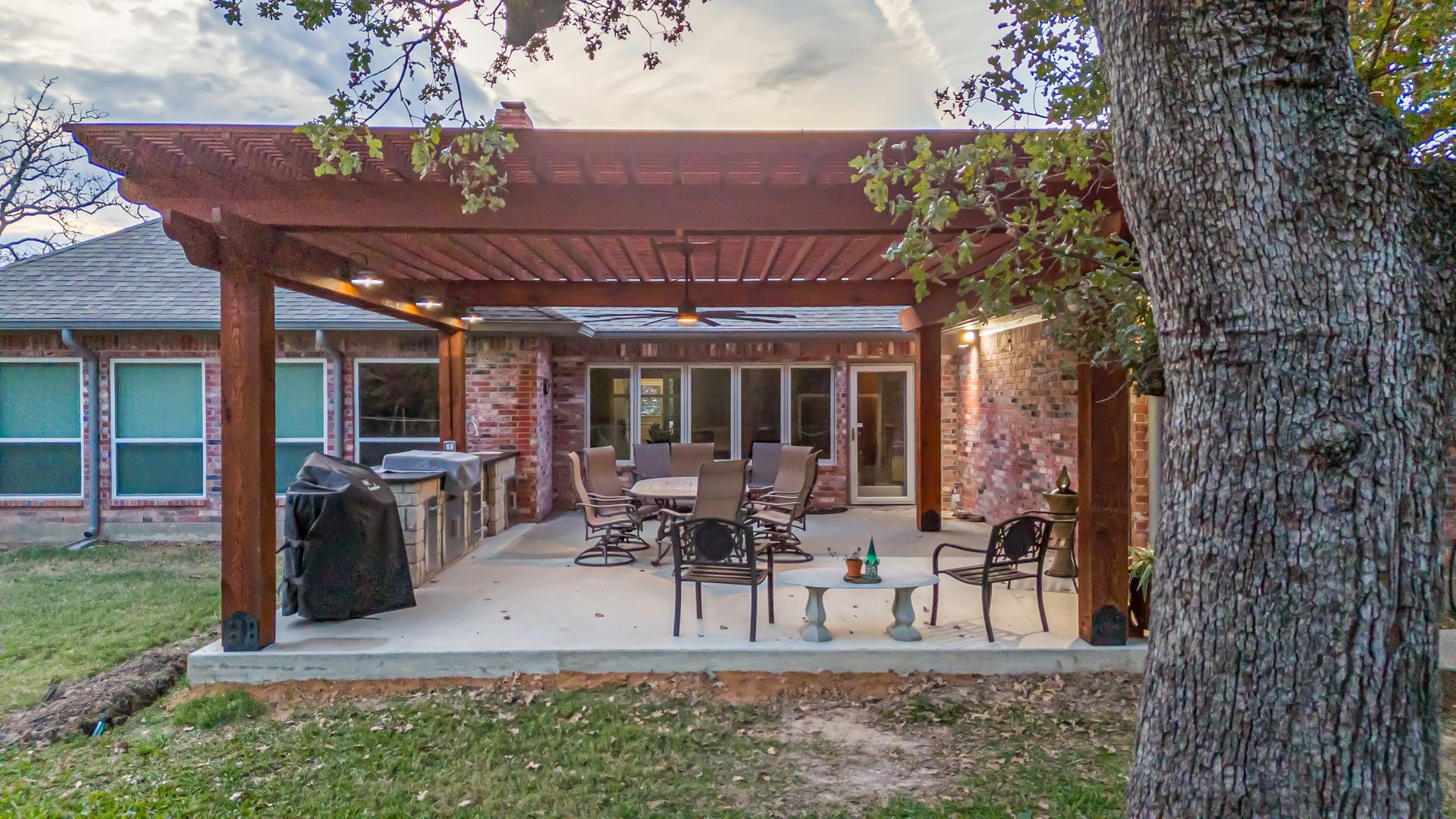 A patio with a pergola and a table and chairs underneath it.