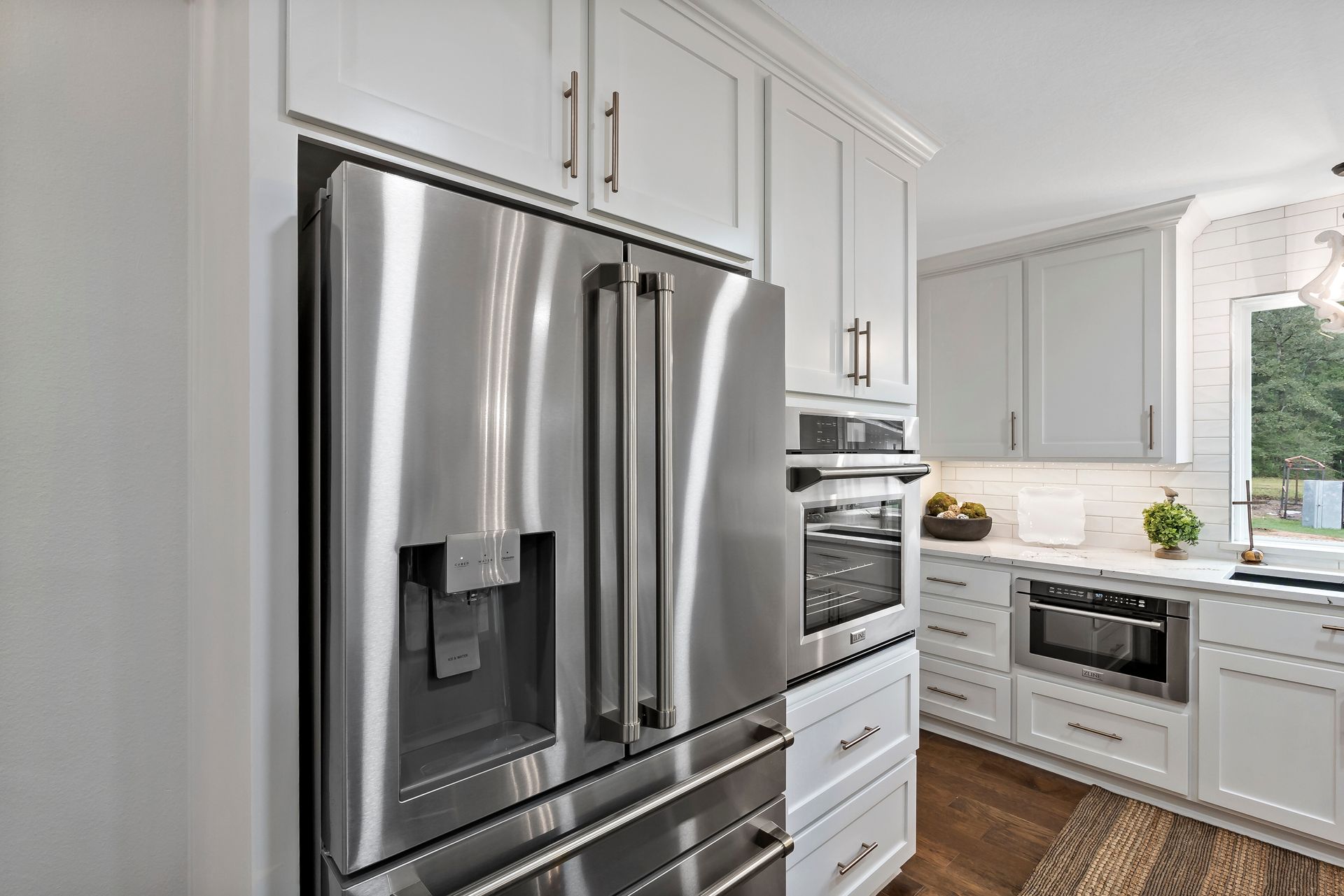 A kitchen with stainless steel appliances and white cabinets.